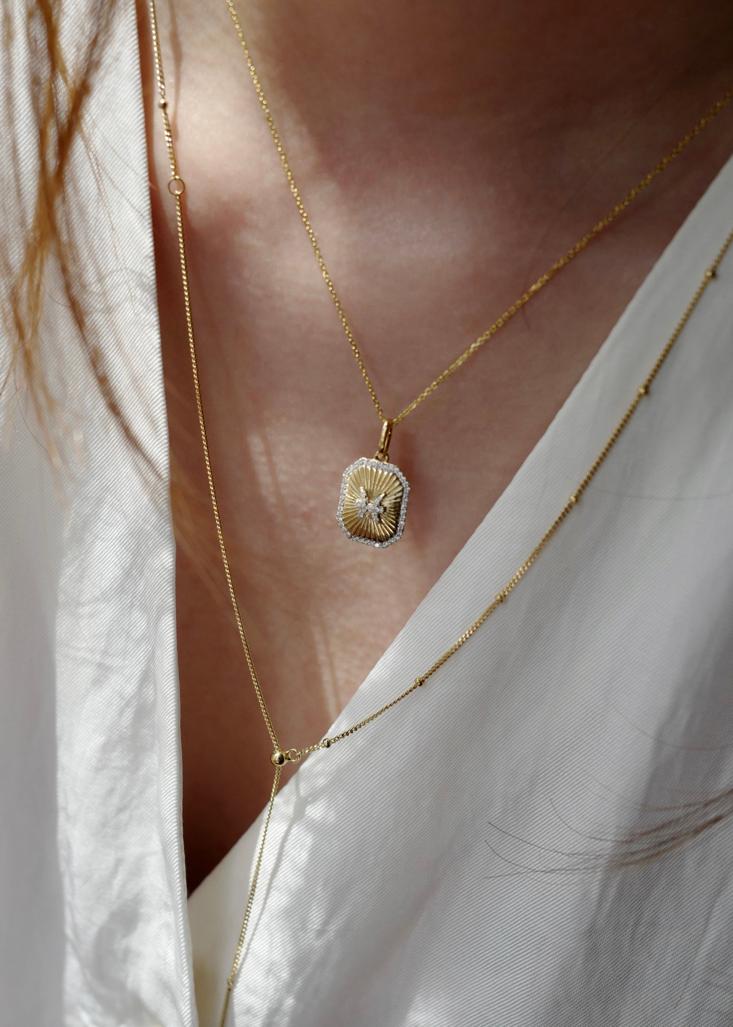 Gold necklace with a pendant on a white shirt
