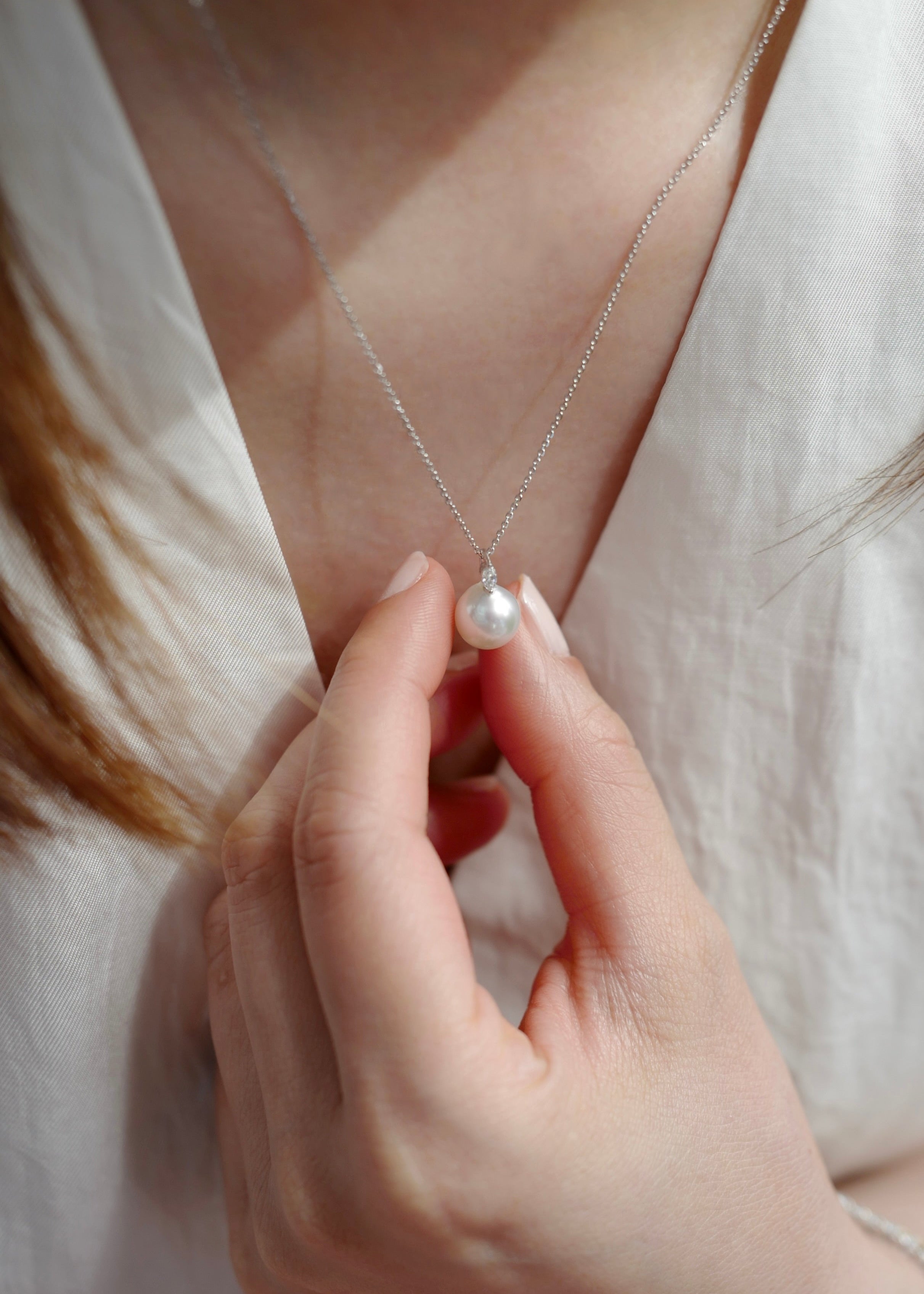 Hand holding a pearl necklace with a soft background
