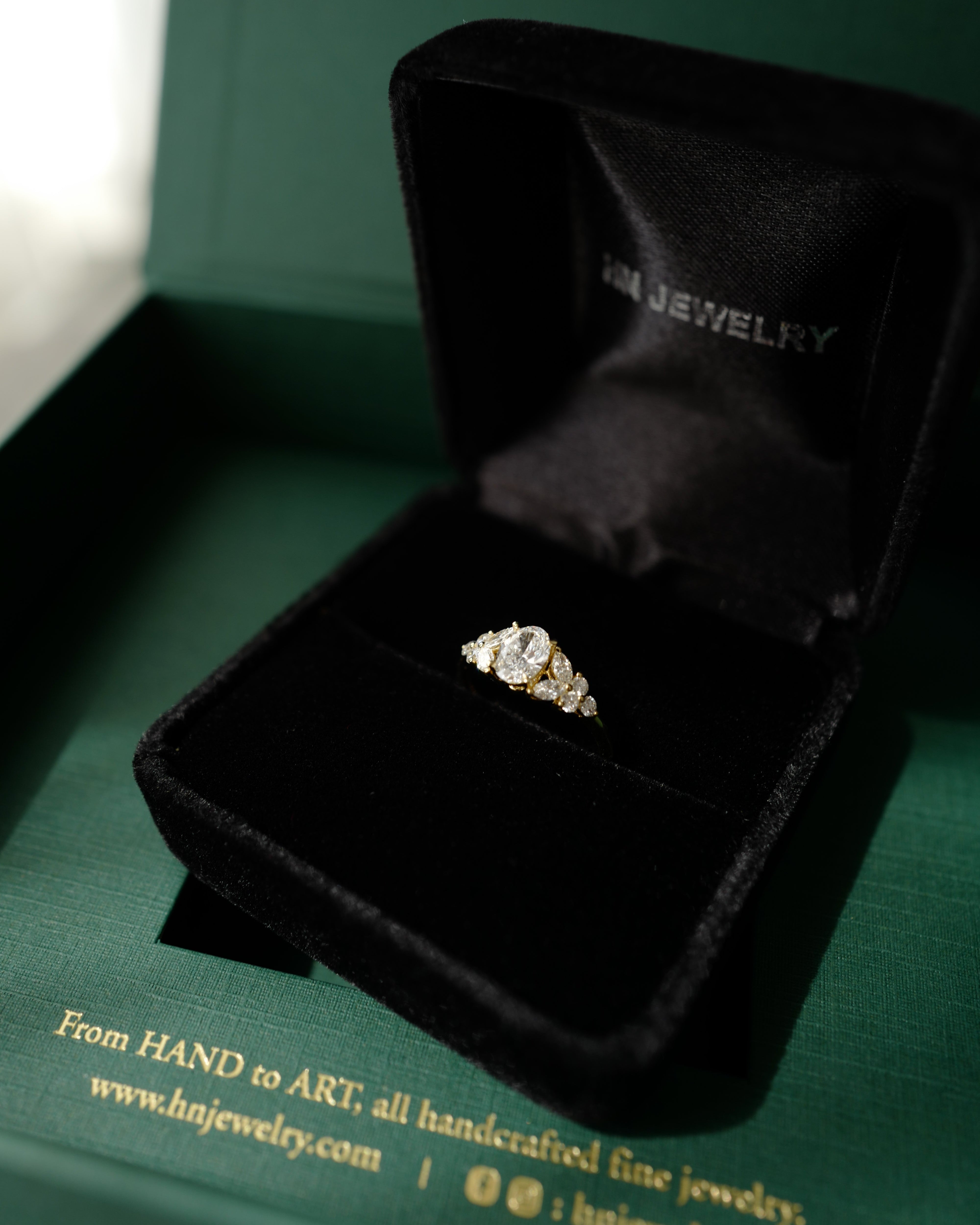 Oval diamond ring in a black jewelry box with 'HN Jewelry' branding on a green background.