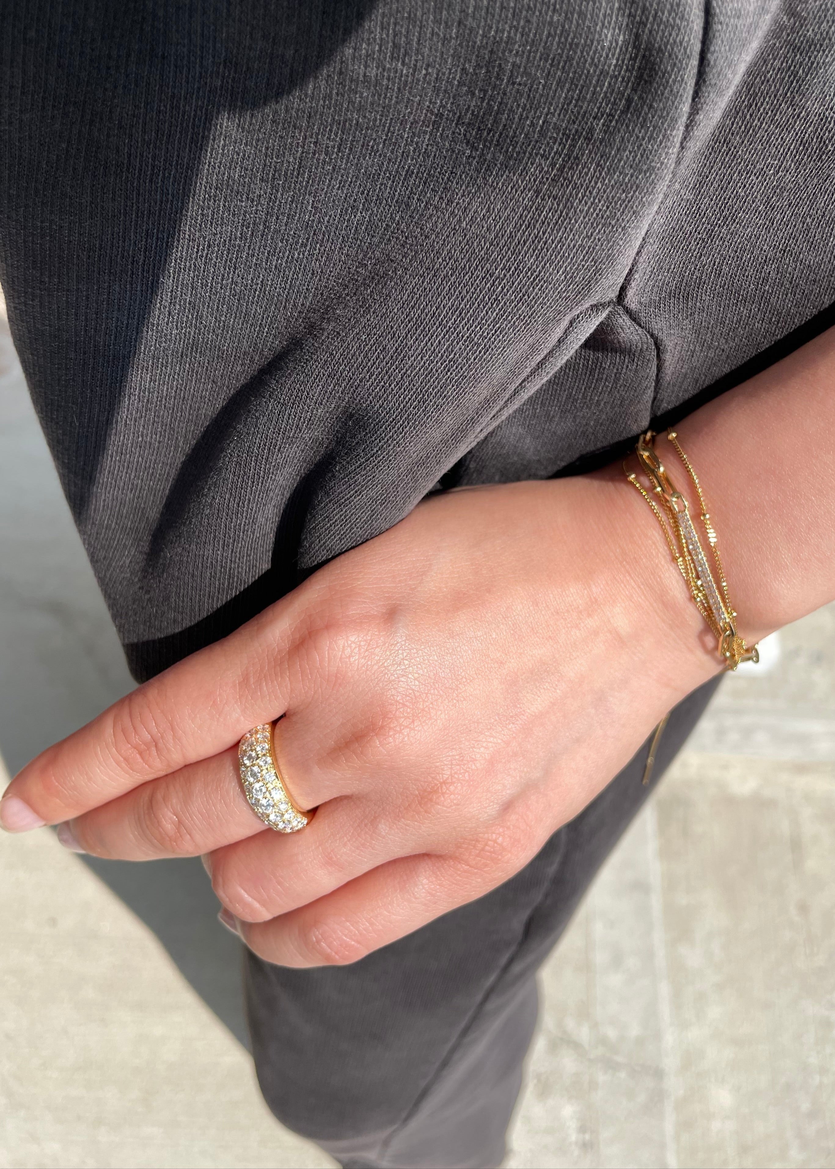 Close-up of a hand wearing a wide diamond ring and bracelet