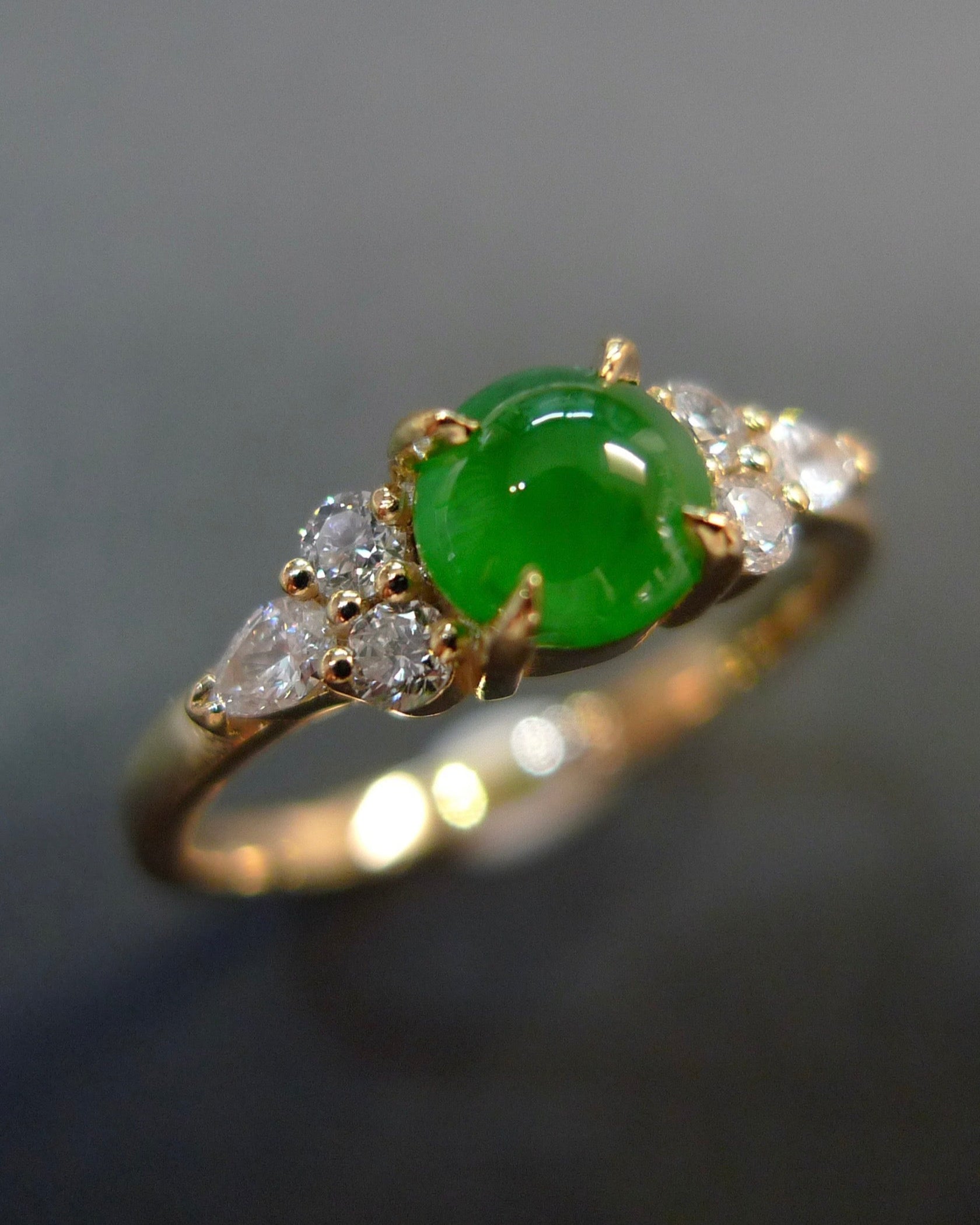 Yellow gold ring with a 5mm round natural green jade at the center and pear diamonds round brilliant diamonds on the side.