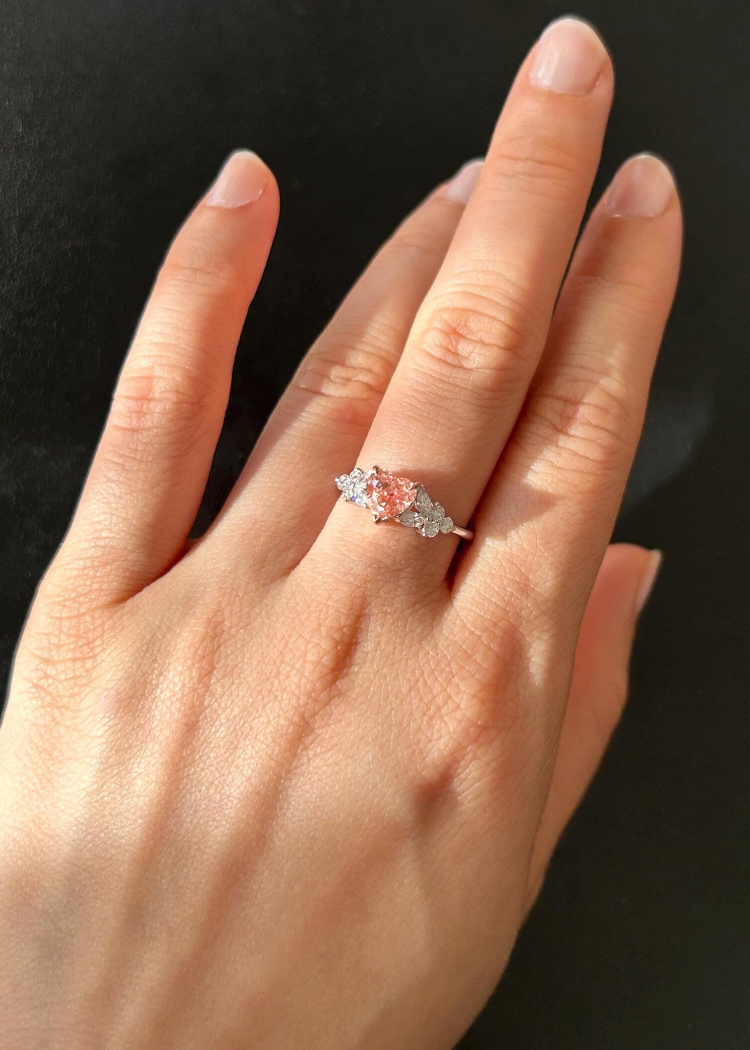 Hand wearing a ring with a pink heart shape diamond and marquise diamond