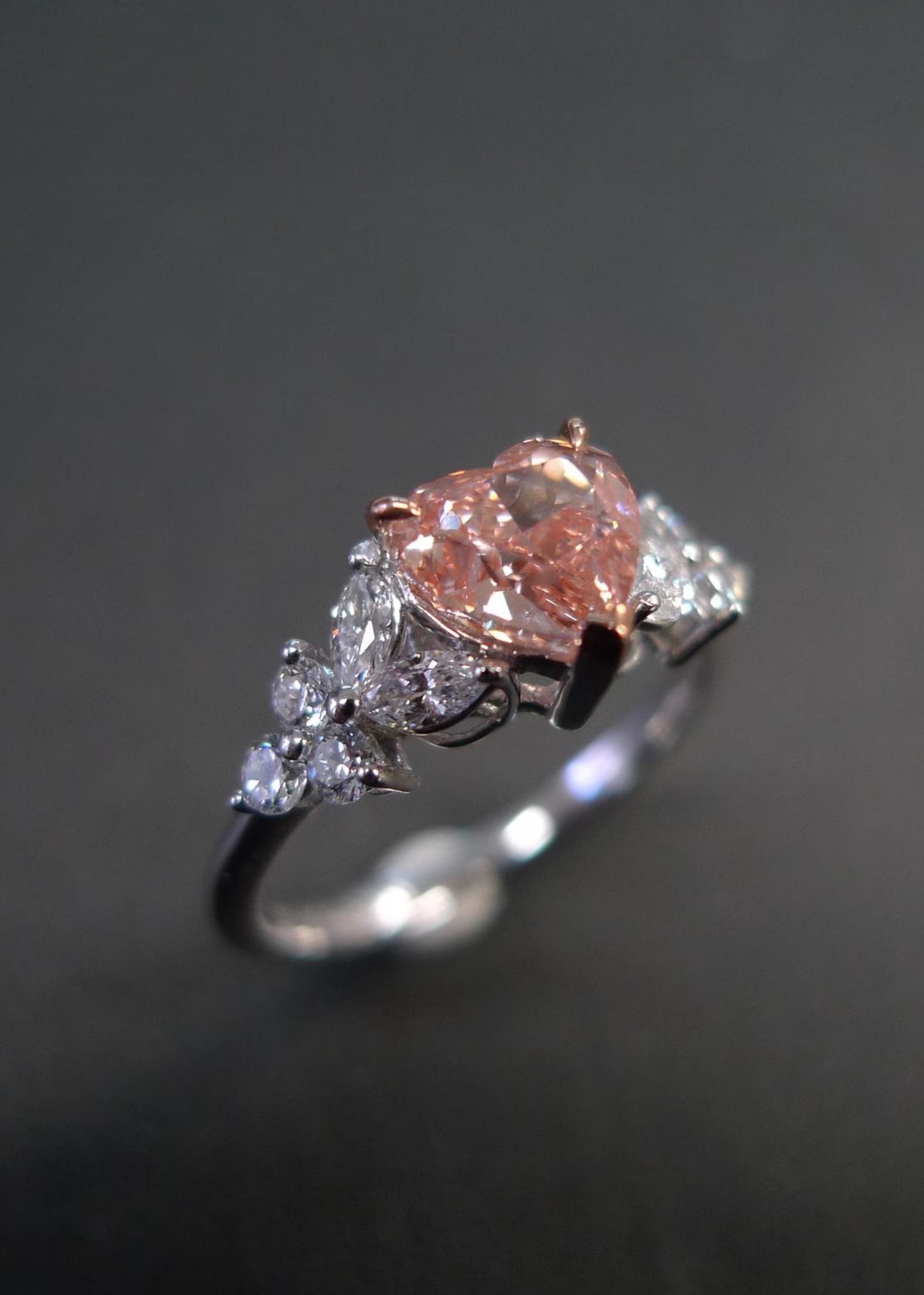 Ring with a pink gemstone and diamond accents on a dark background
