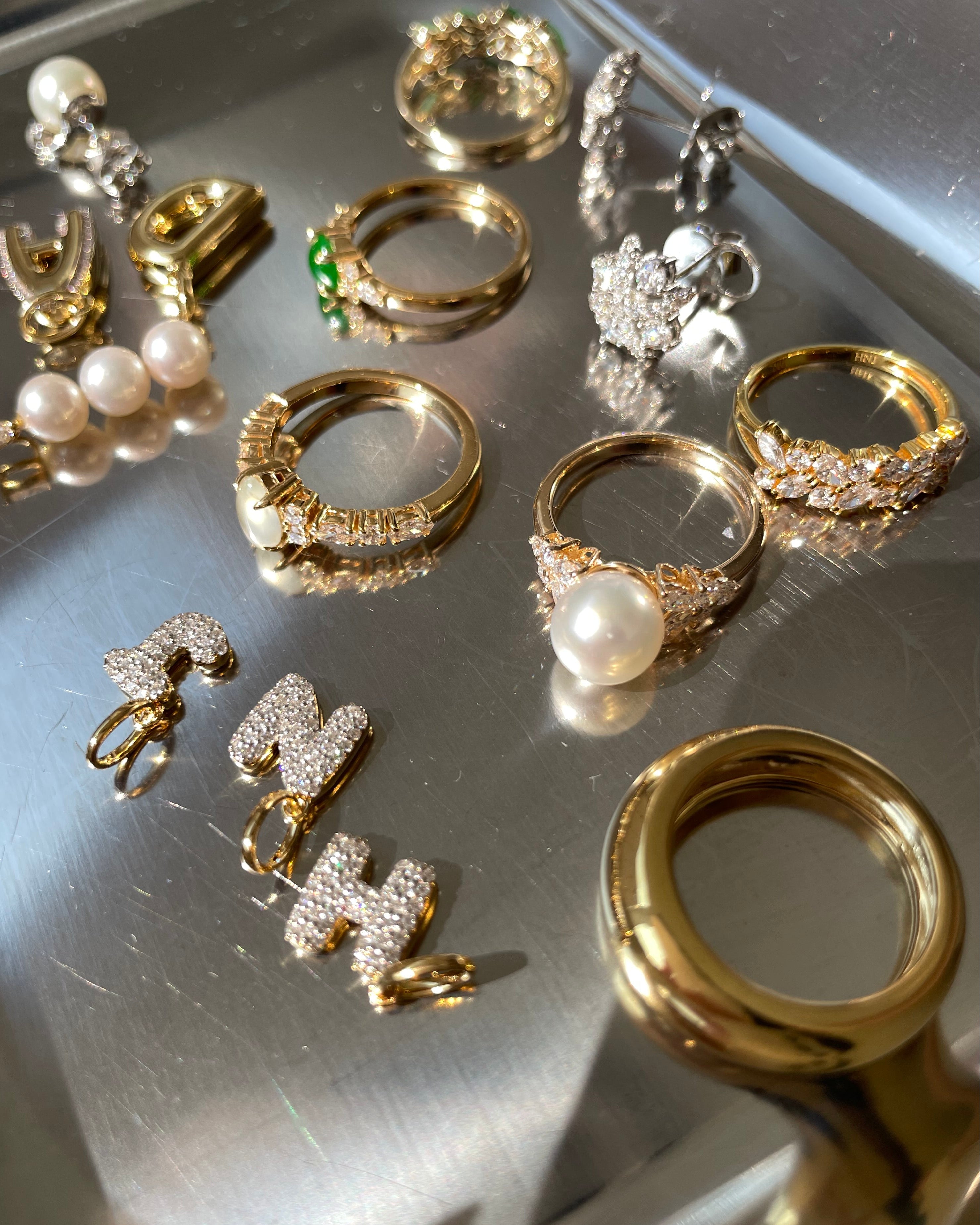Collection of HN Jewelry gold jewelry on a metallic surface
