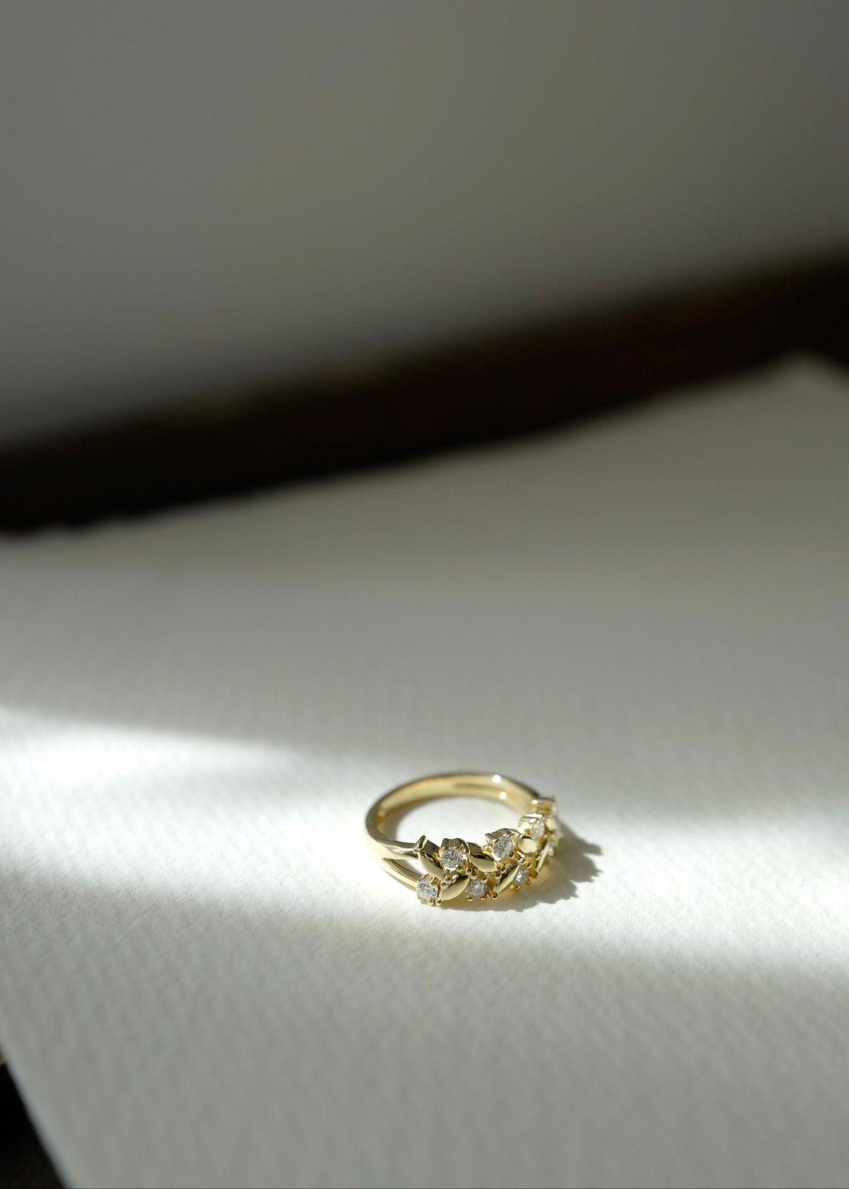 A gold band ring with a row of round brilliant diamonds, photographed close up on a white surface.