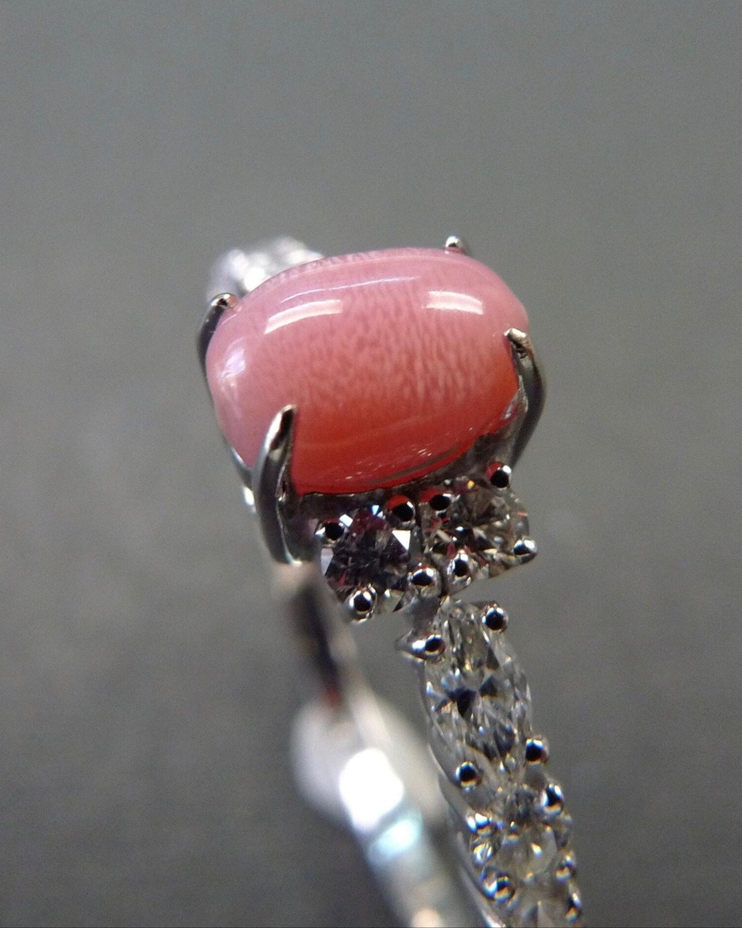 Ring with a pink gemstone and silver accents on a gray background