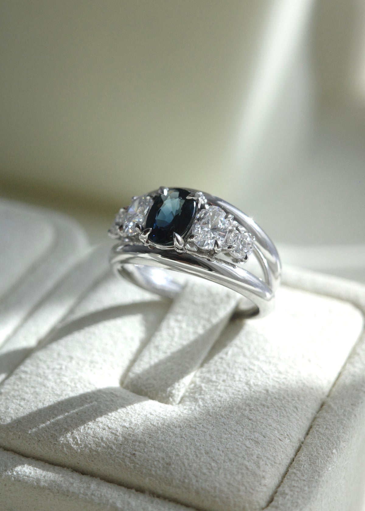 Macro close-up of deep teal sapphire center stone and diamond prongs in 14k white gold.