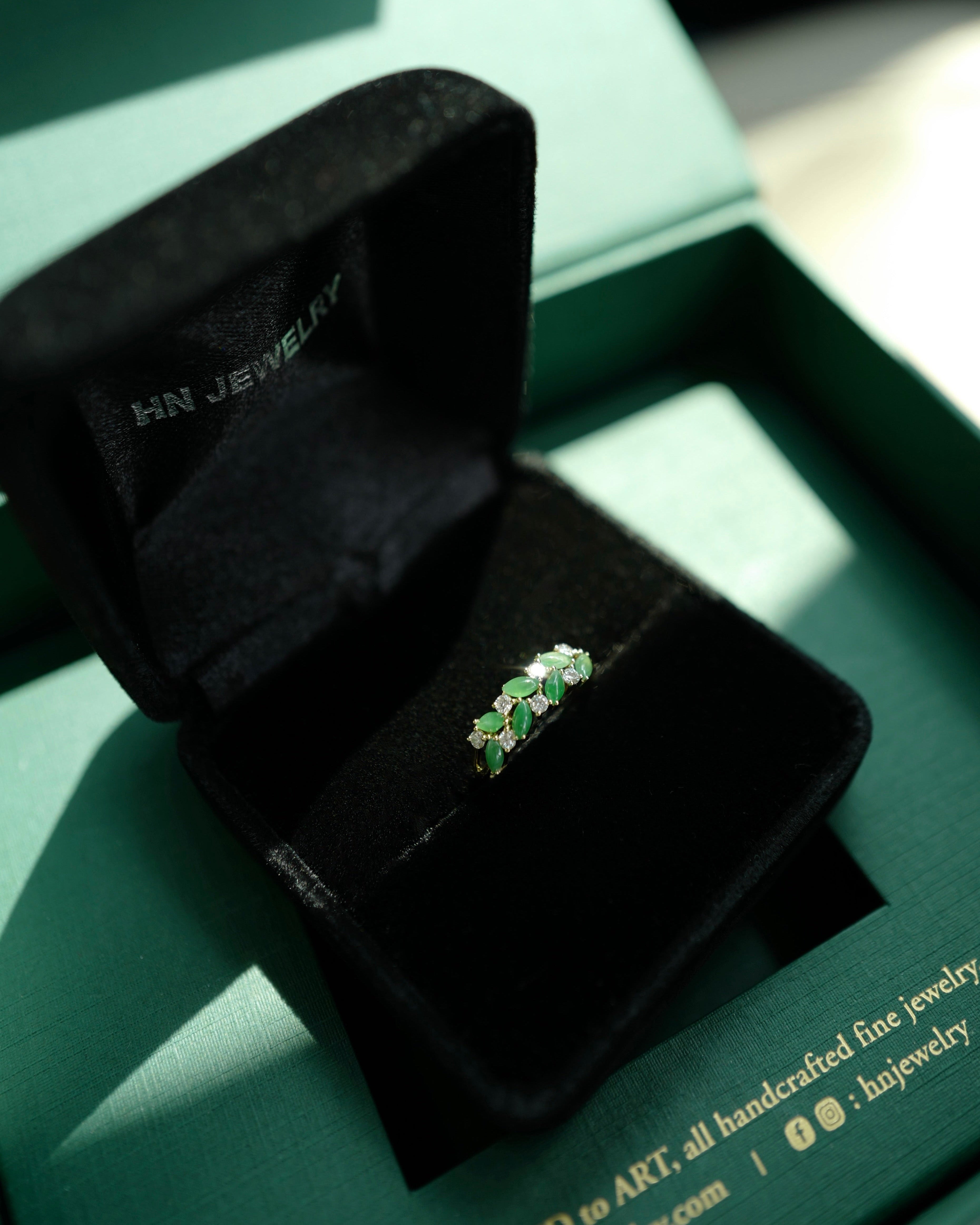 Green jades and diamonds ring in a black jewelry box on a green packaging box