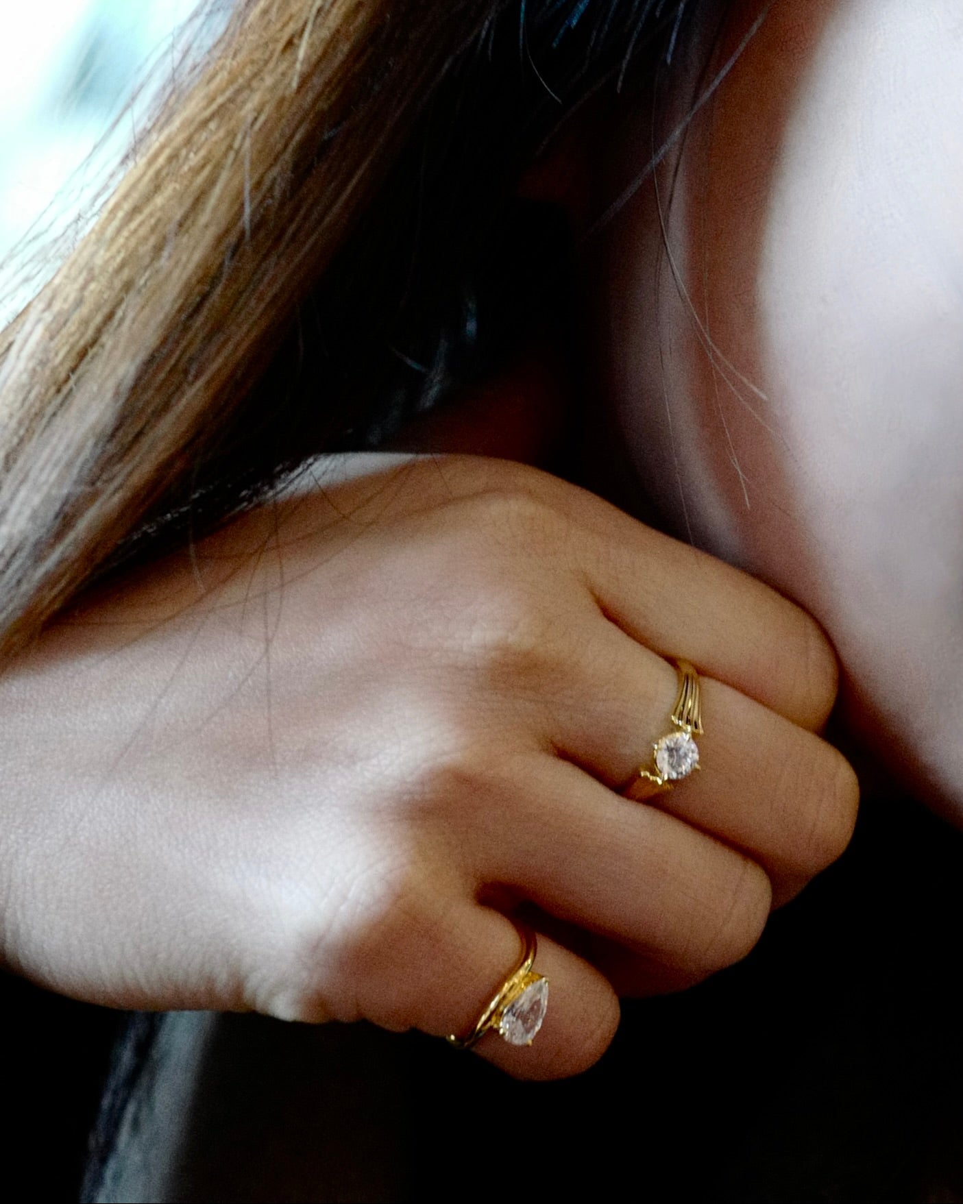 Close-up of a hand with gold pinky ring on fingers, blurred background