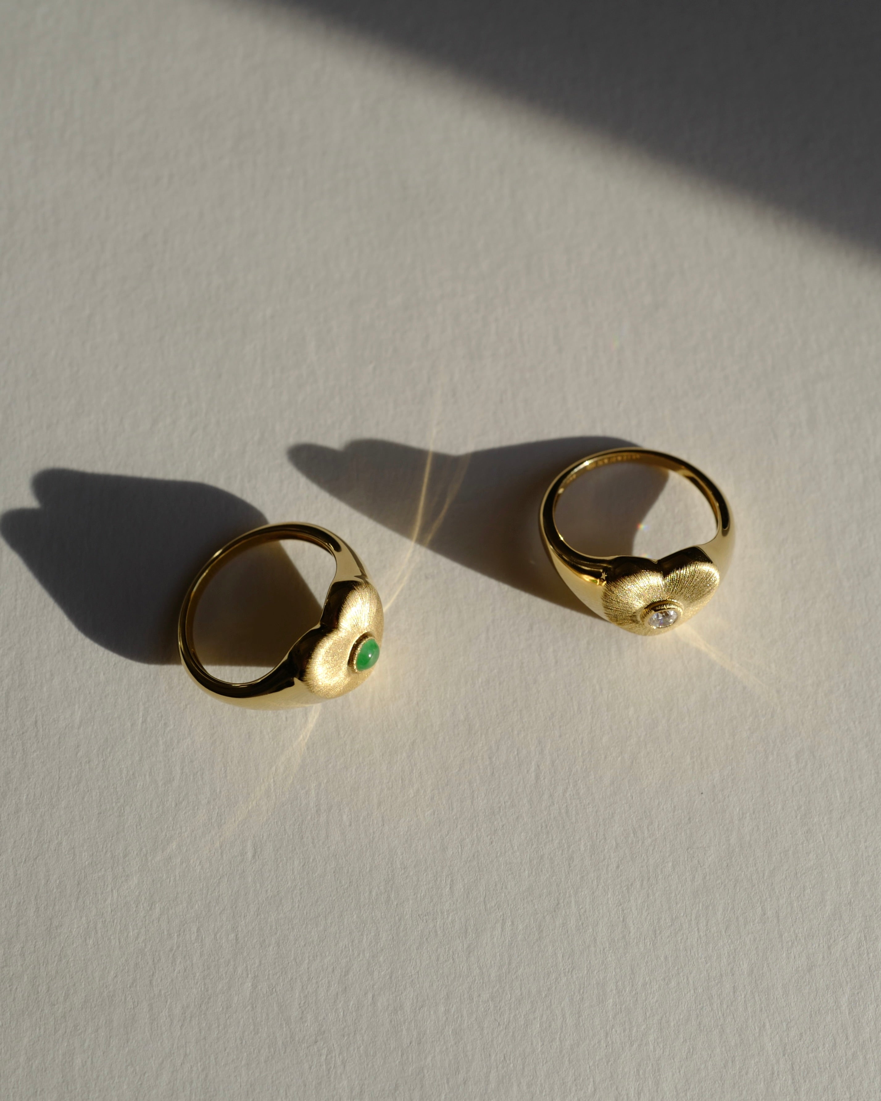 Two gold texture signet rings with gemstones on a light surface