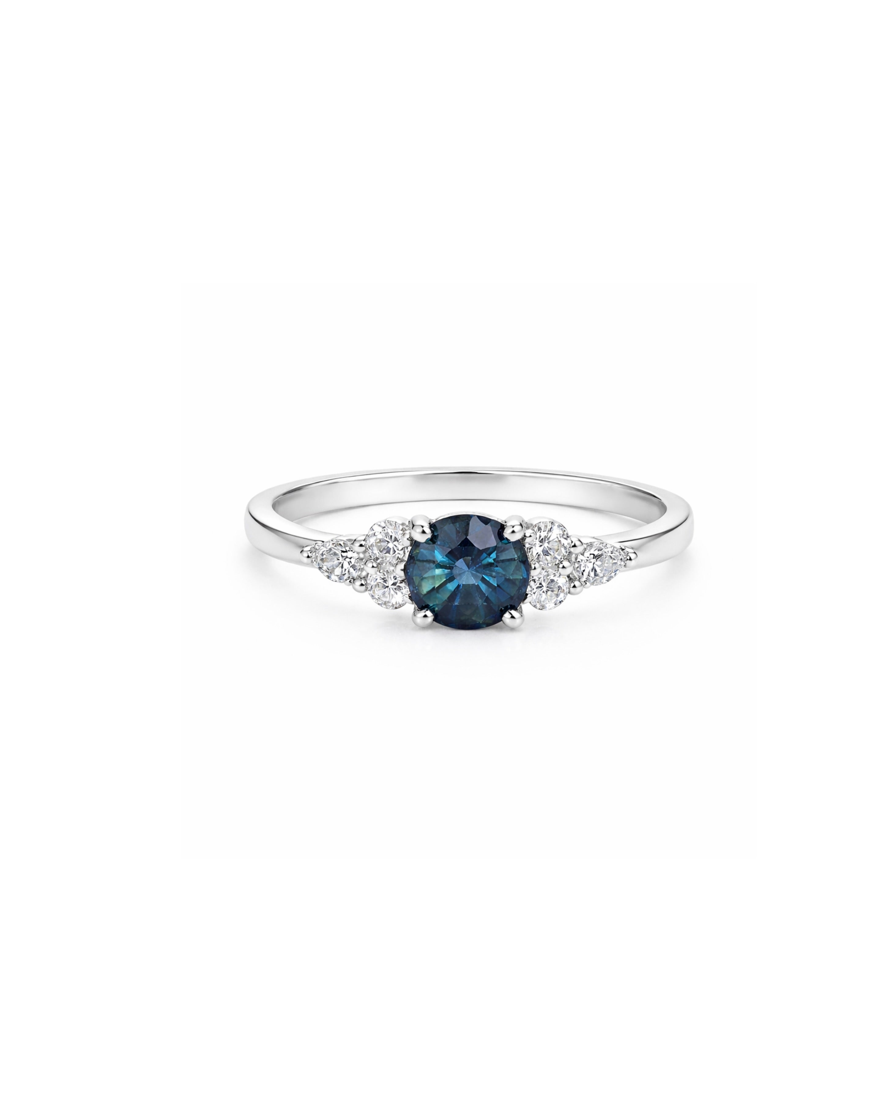 A ring featuring a round teal sapphire center stone with round and pear cut diamonds flanking on either side, set in 14K white gold.