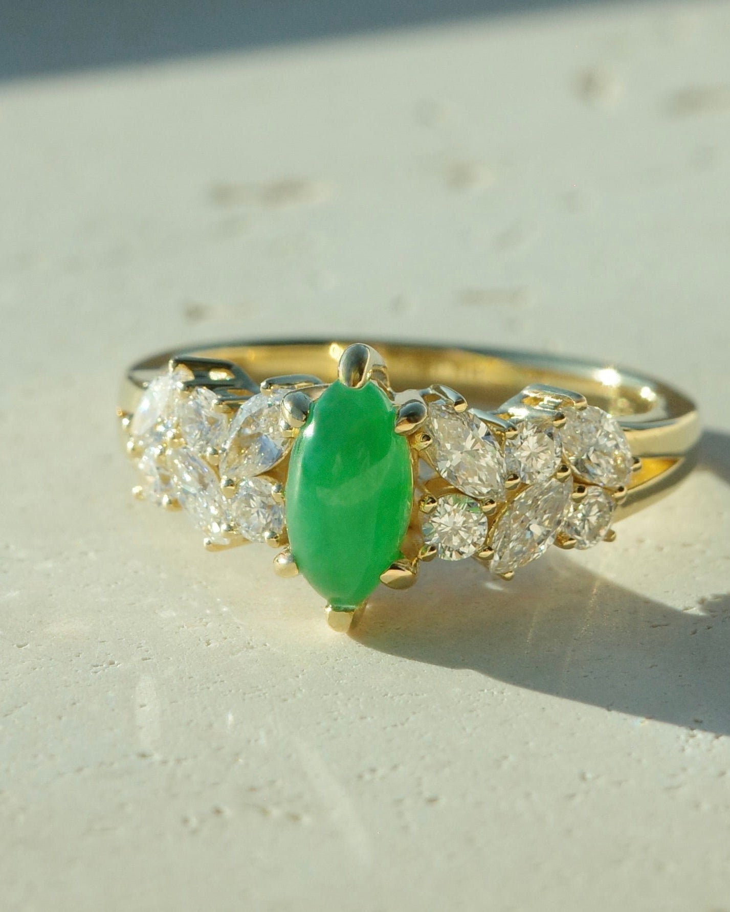 14K solid gold ring with a green natural jade and diamond accents on a light surface