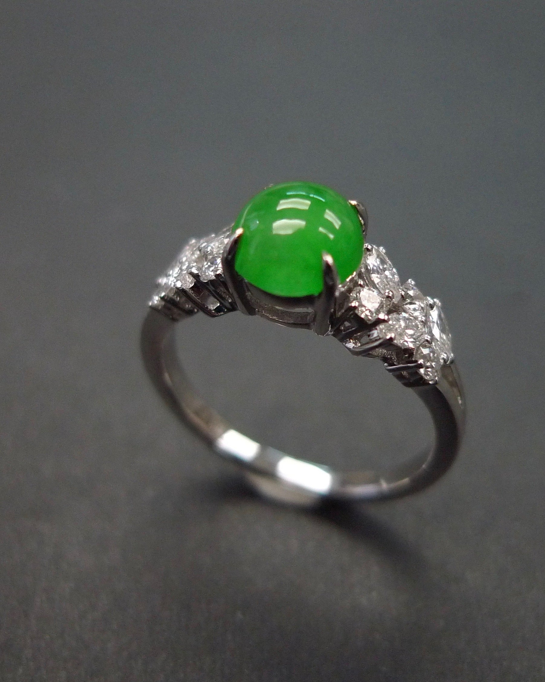 a women ring set with green round jade at the center along with marquise diamond on the side