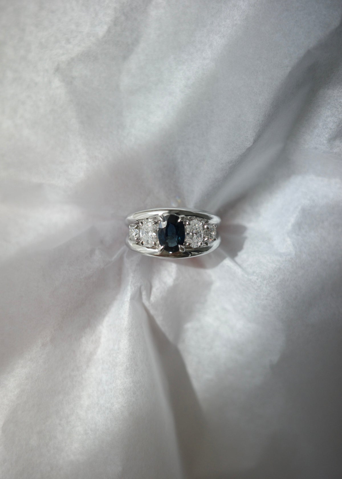 Sunlight passing through natural oval teal sapphire showing rich blue and green hues.