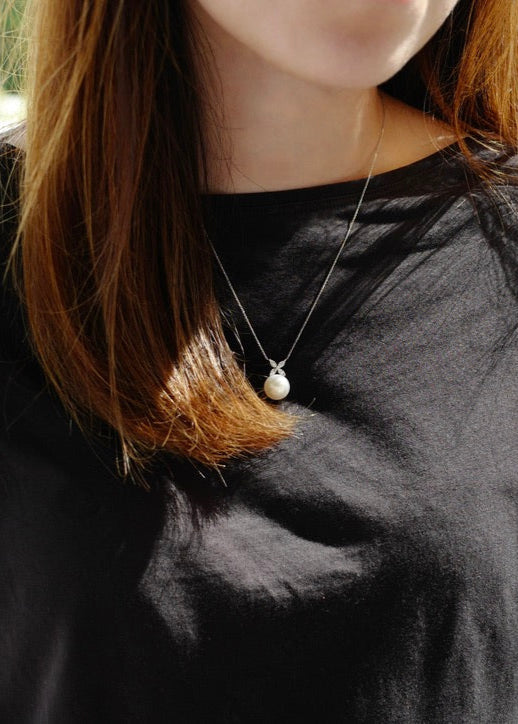 Person wearing a black long-sleeve shirt with a necklace outdoors