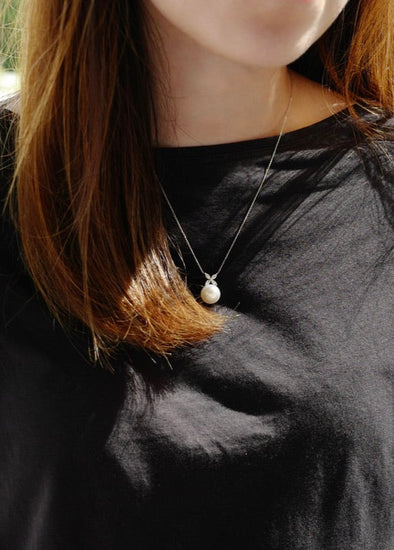 Person wearing a black long-sleeve shirt with a necklace outdoors