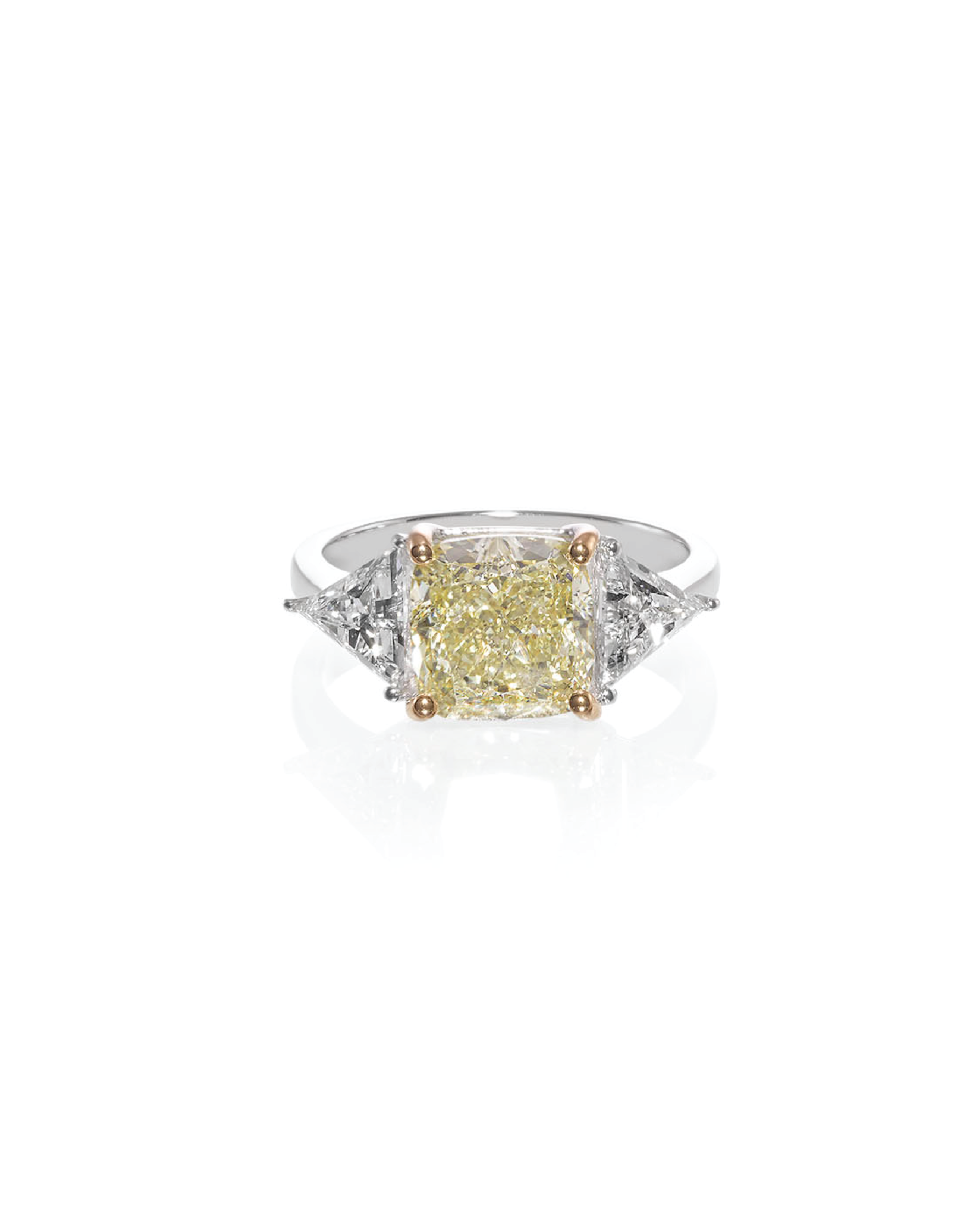 A cushion fancy yellow diamond ring with two triangle diamonds on the side, set in a white gold band.