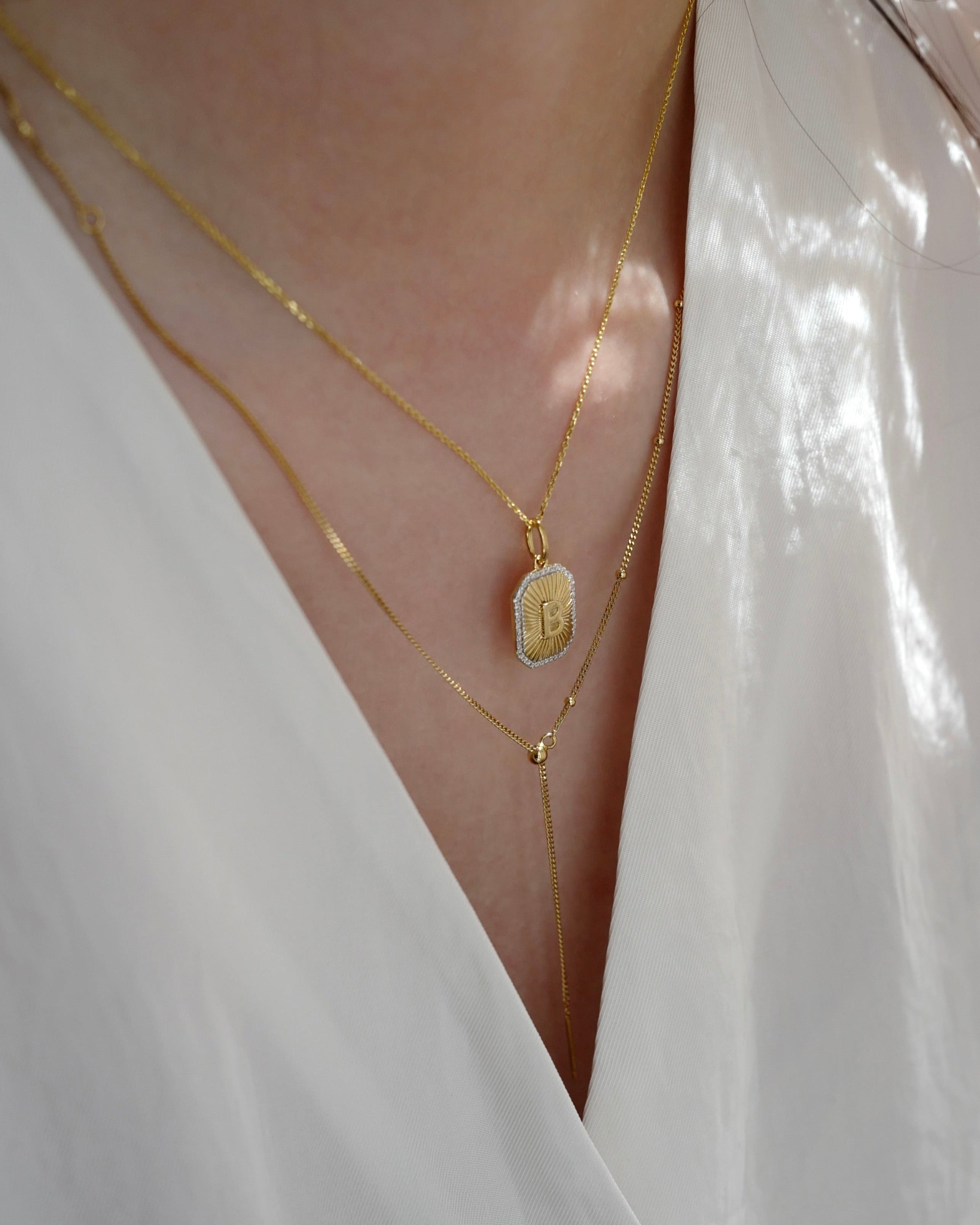Close-up of a person wearing gold necklaces with a white garment.