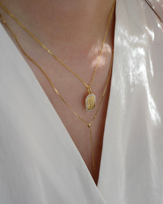 Close-up of a person wearing gold necklaces with a white garment.