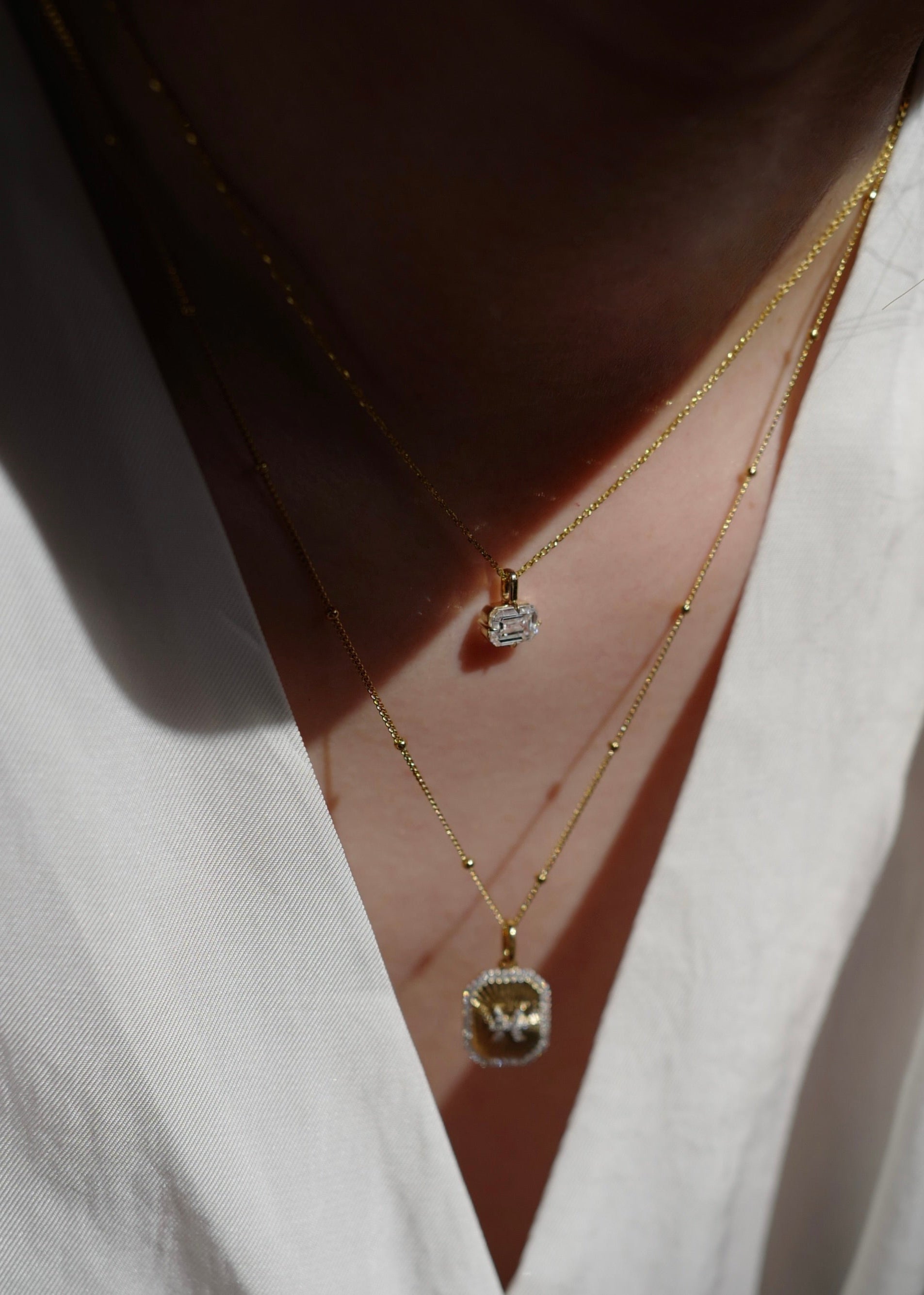 Close-up of a person wearing a white shirt with layered gold necklaces.