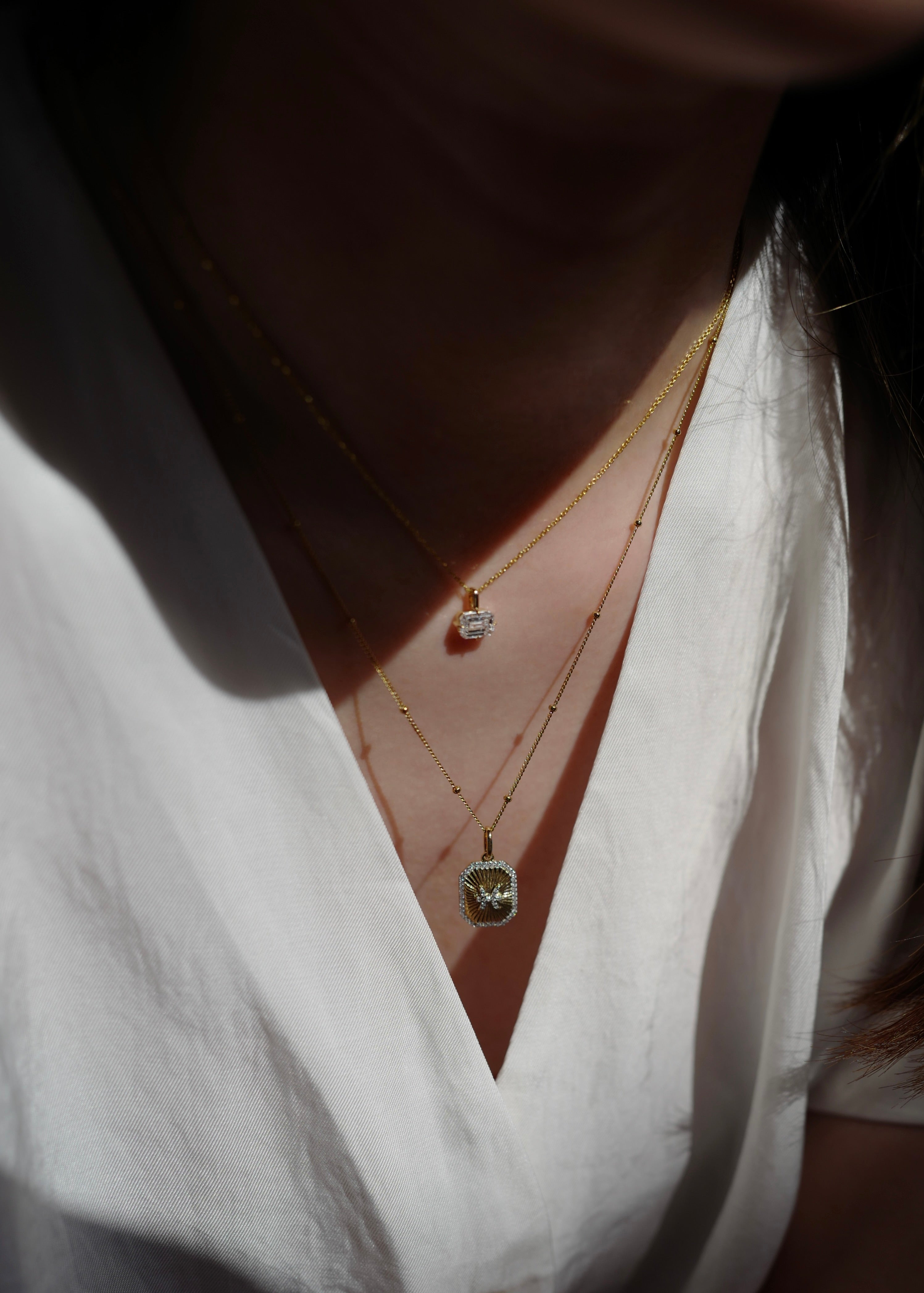 Close-up of a person wearing a white shirt with a necklace and earrings.