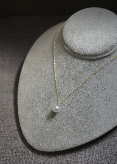 Pearl necklace on a gray jewelry display