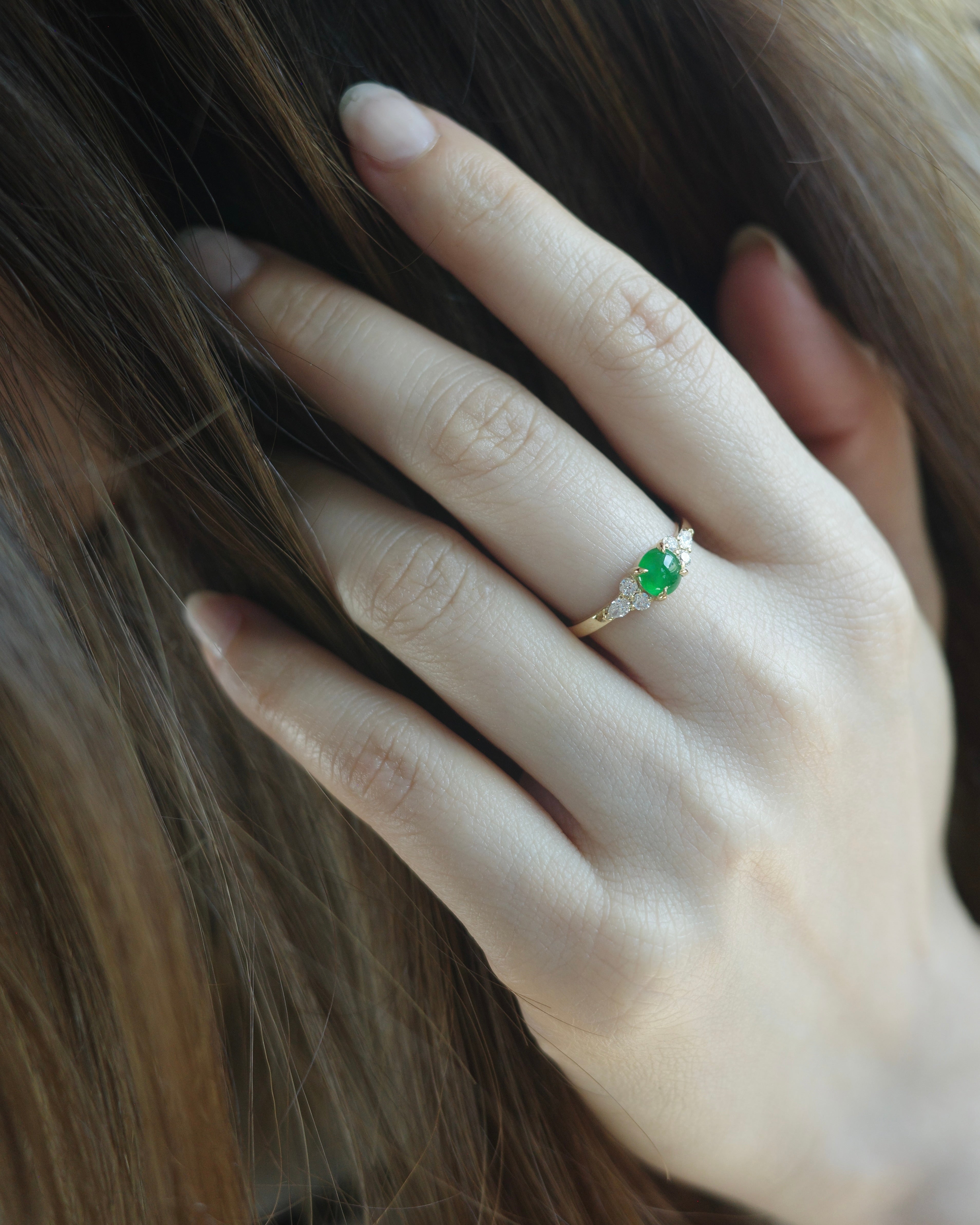 Close-up of a hand wearing a ring with a green jade and gold band.