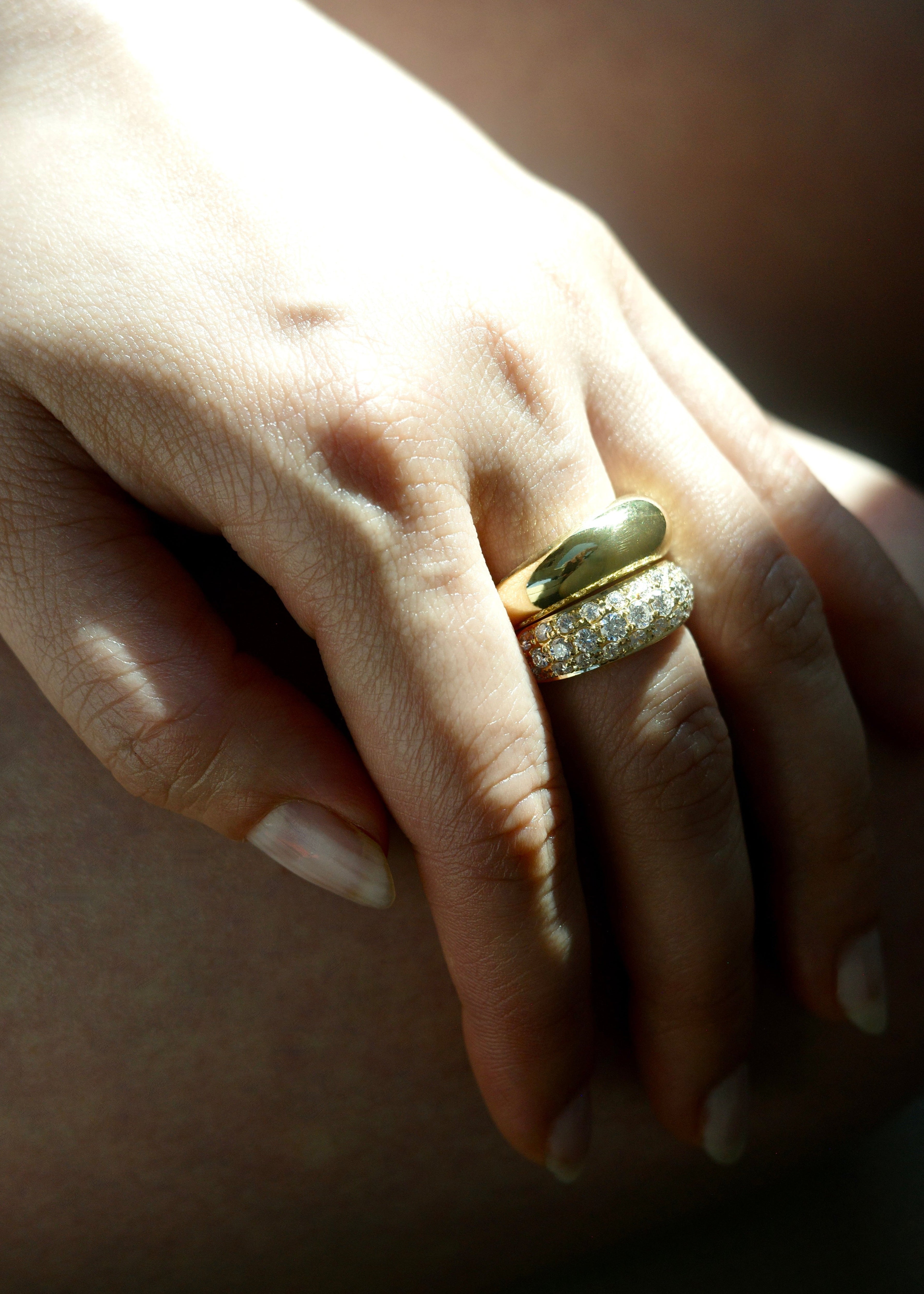 Close-up of a hand wearing two wide gold rings 