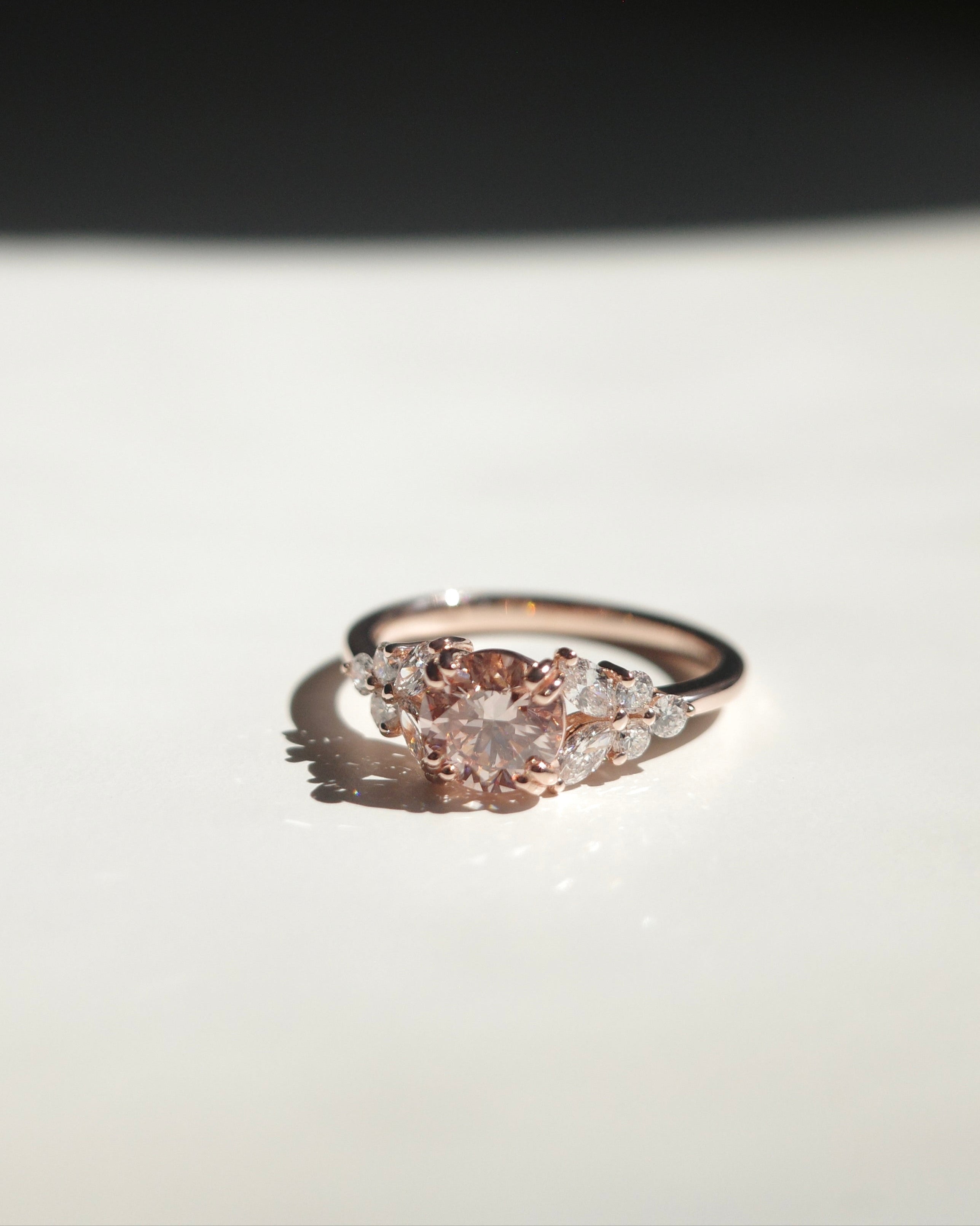 Rose gold ring with a round pink diamond at the center along with marquise diamond on the side.