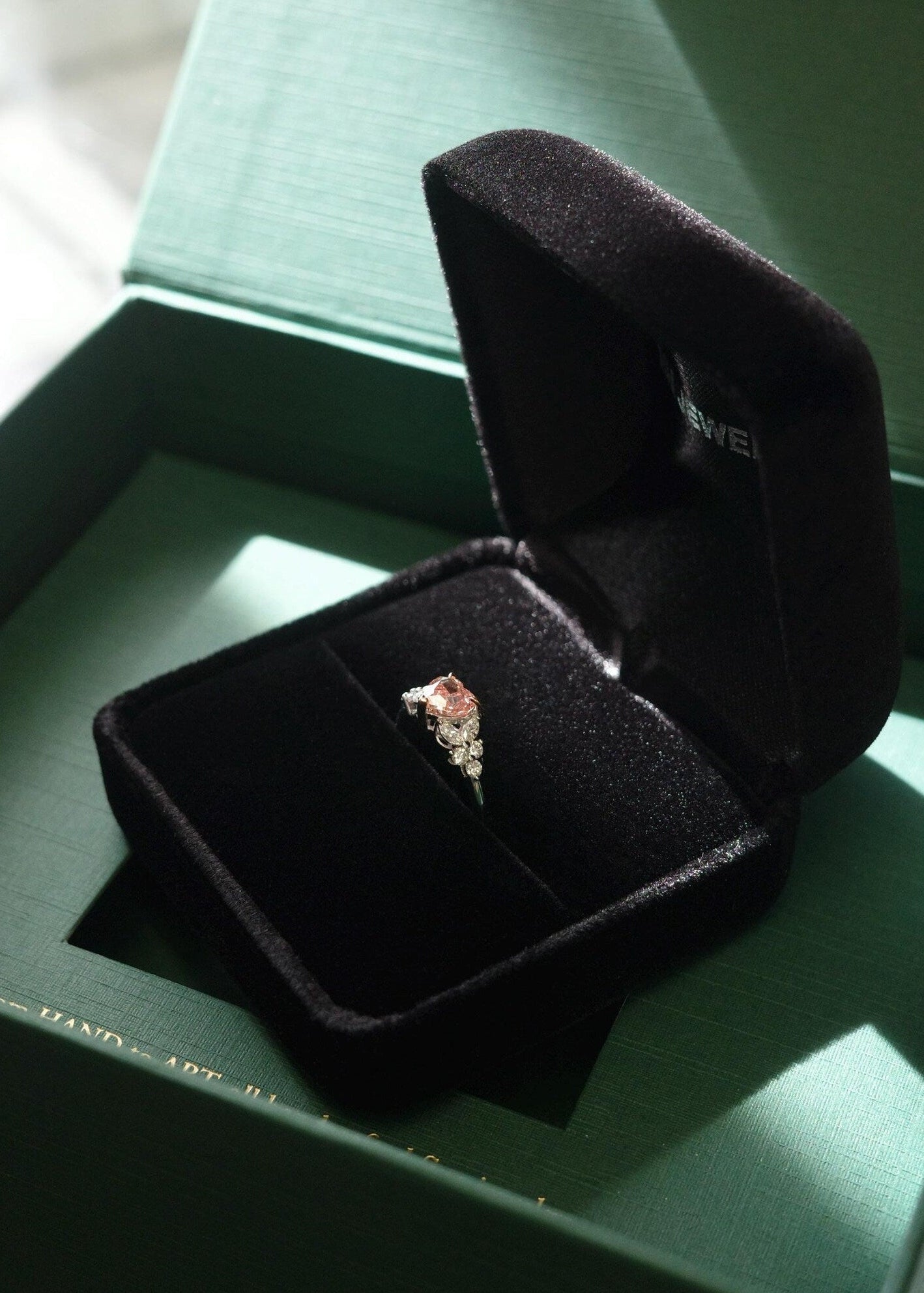 Open black jewelry box with a pink diamond ring 
