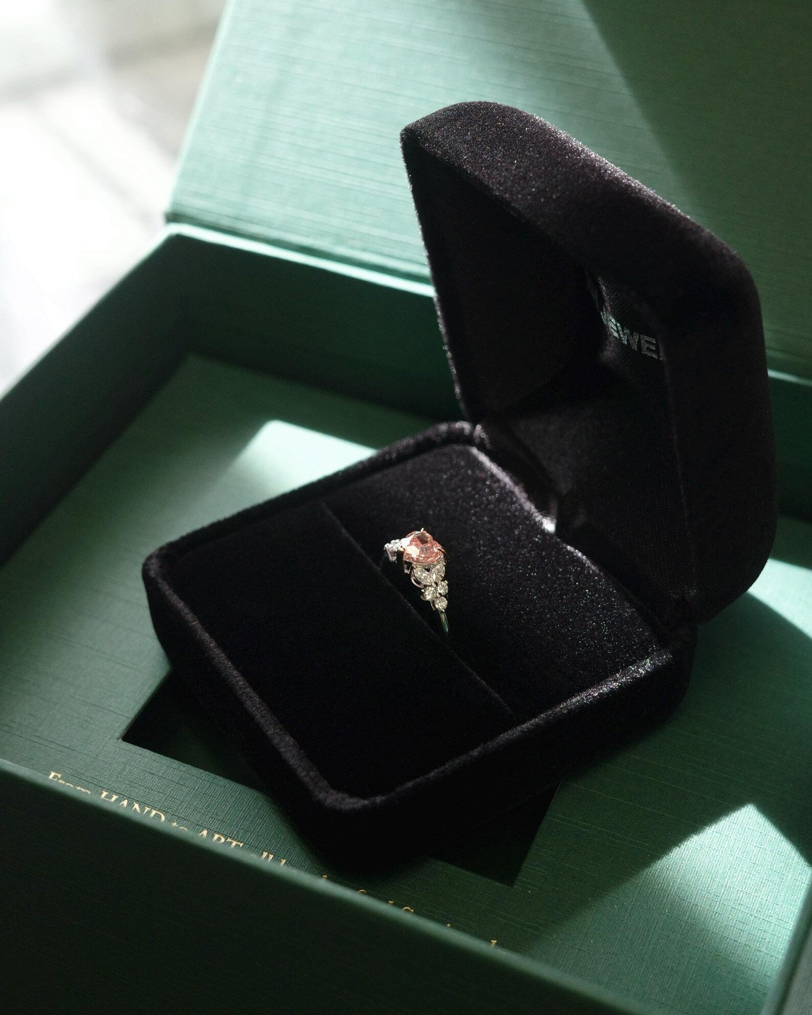 Open black jewelry box with a pink diamond ring 