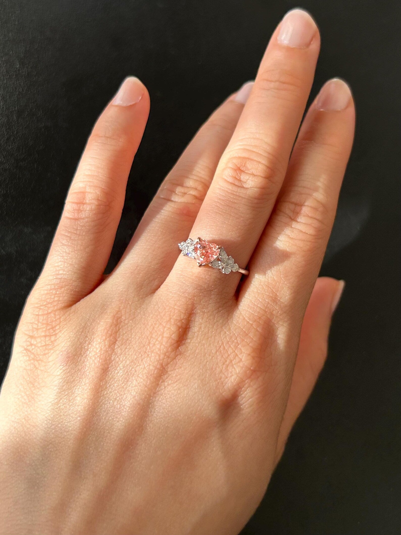 Hand wearing a ring with a pink heart shape diamond and marquise diamond