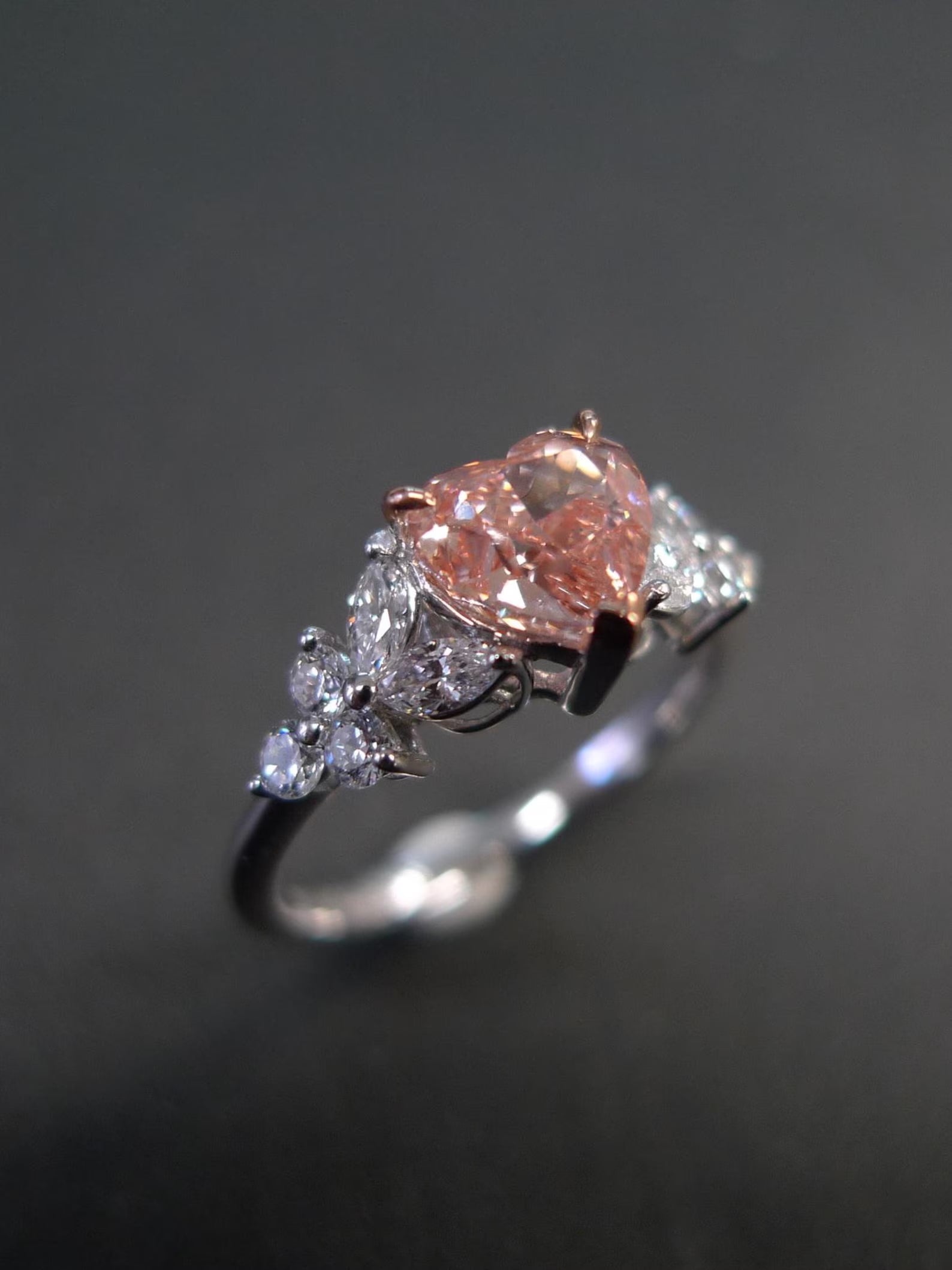 Ring with a pink gemstone and diamond accents on a dark background