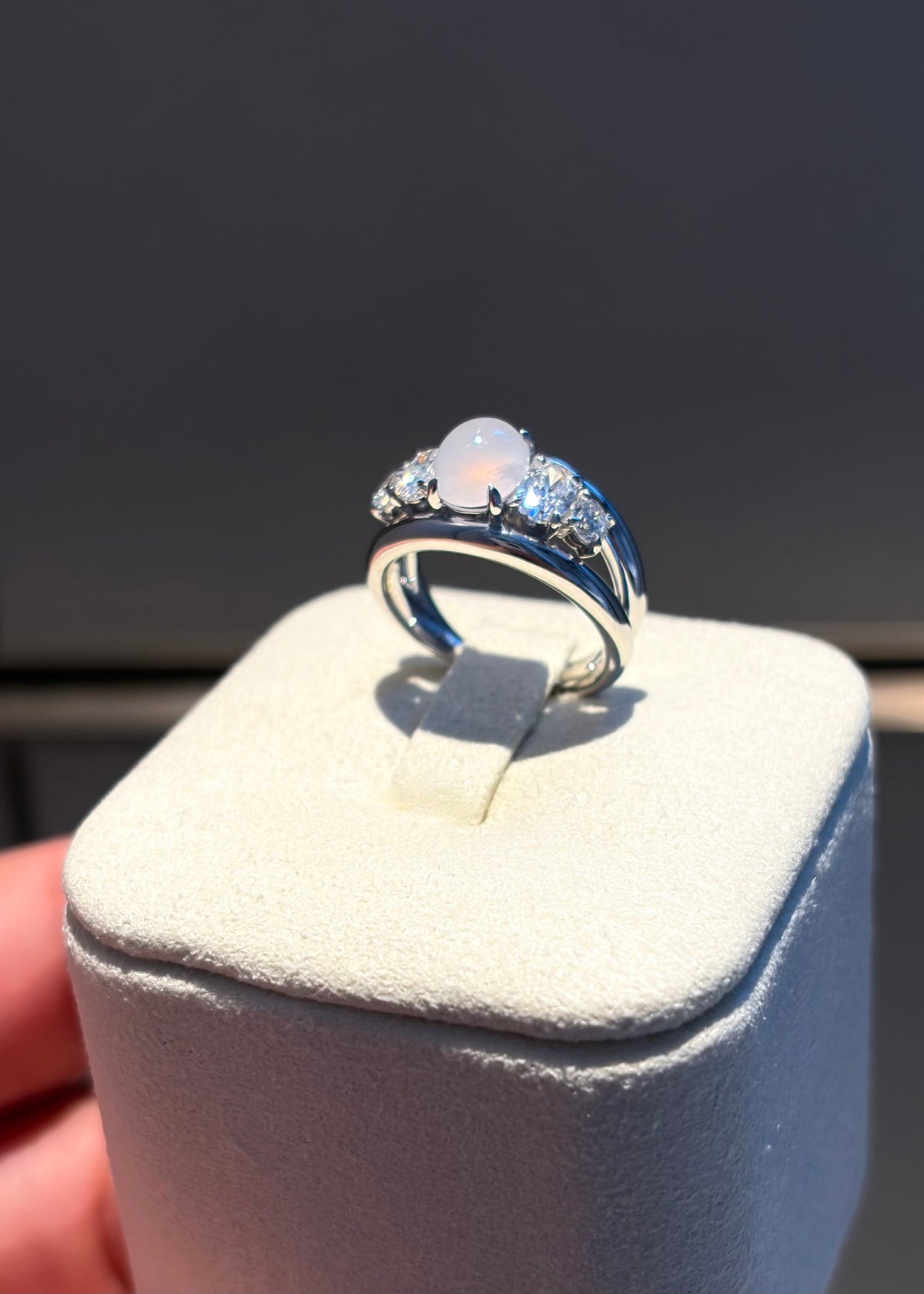 Macro close-up of translucent icy white jade cabochon and diamond prongs in 14k white gold.
