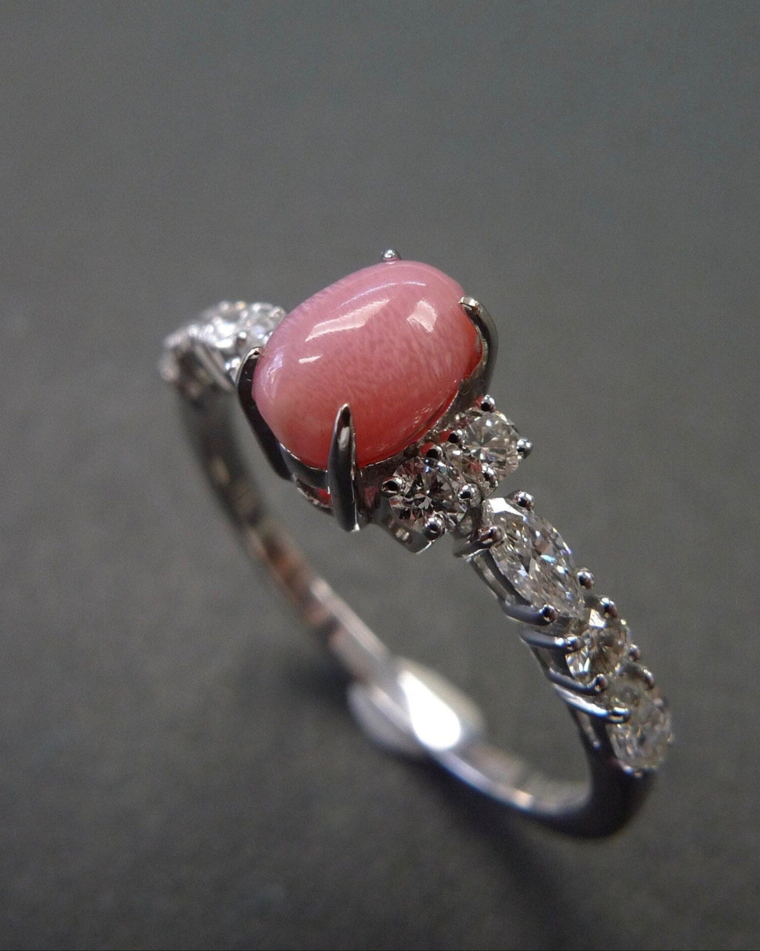 Ring with a conch pearl and diamond-studded band on a dark background