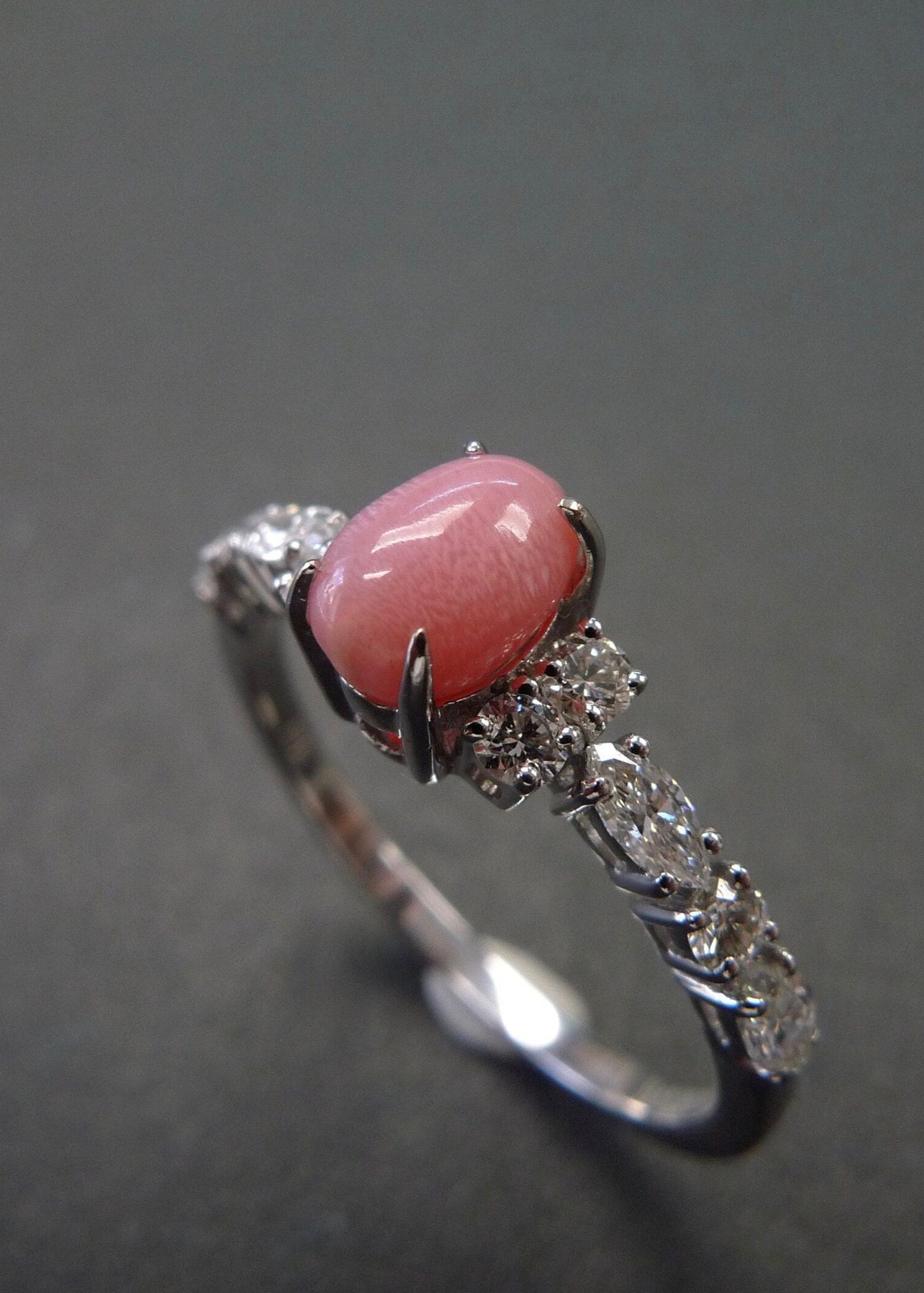 Ring with a conch pearl and diamond-studded band on a dark background