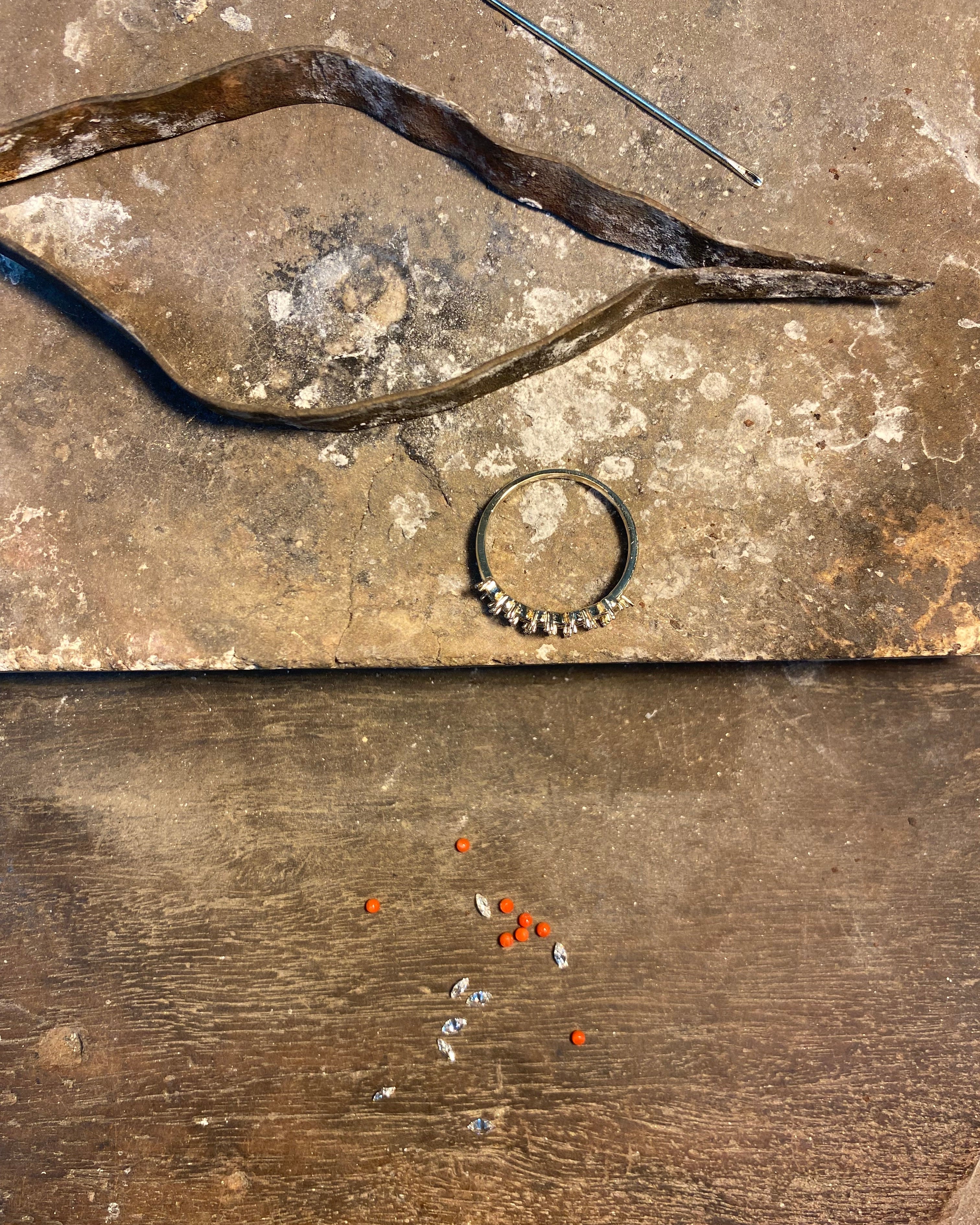 jeweler table, ring, and small stones on a stone surface