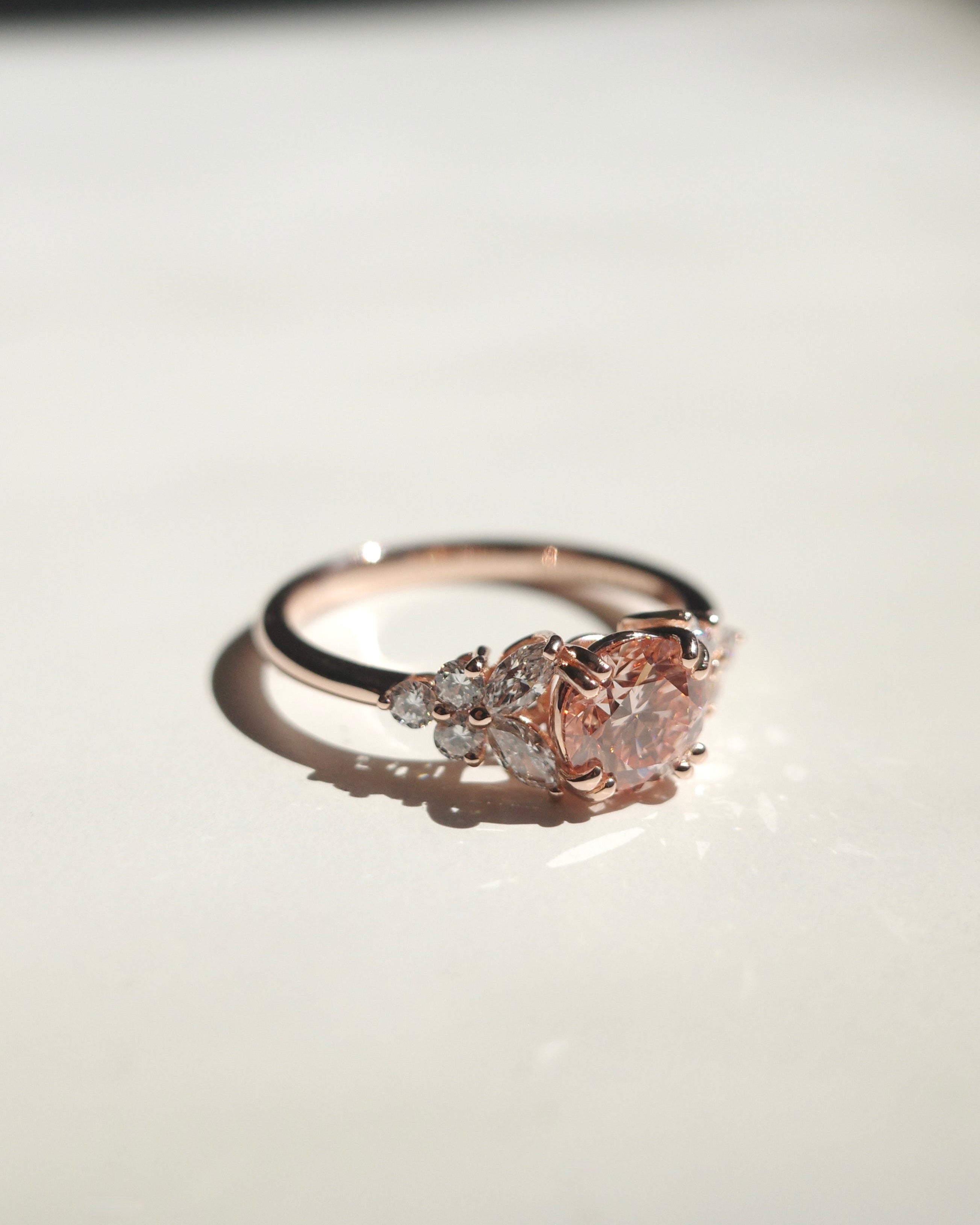 Rose gold ring with a round shaped lab grown pink diamond on a light background