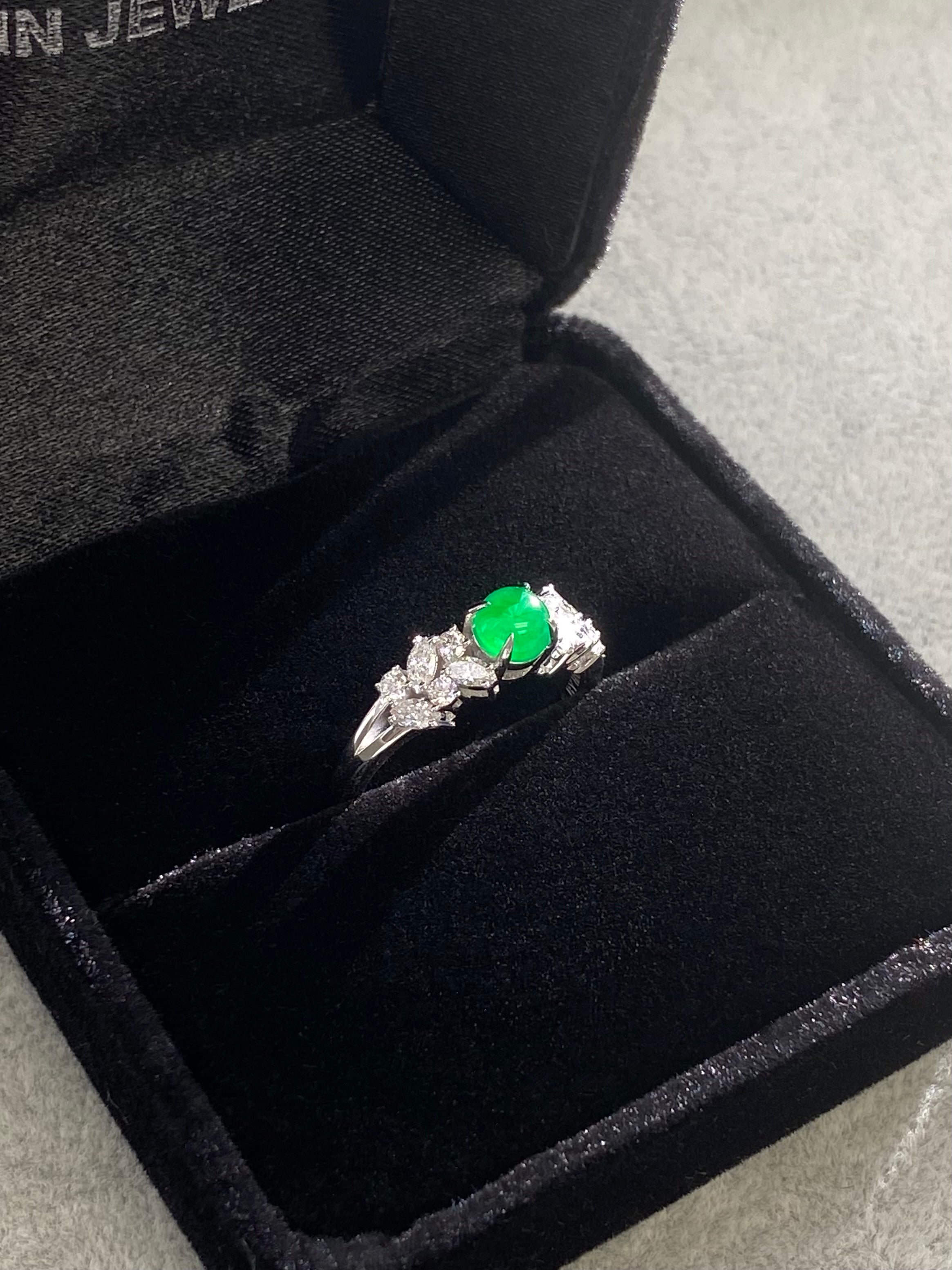 Green round jade and marquise diamond ring in a black jewelry box