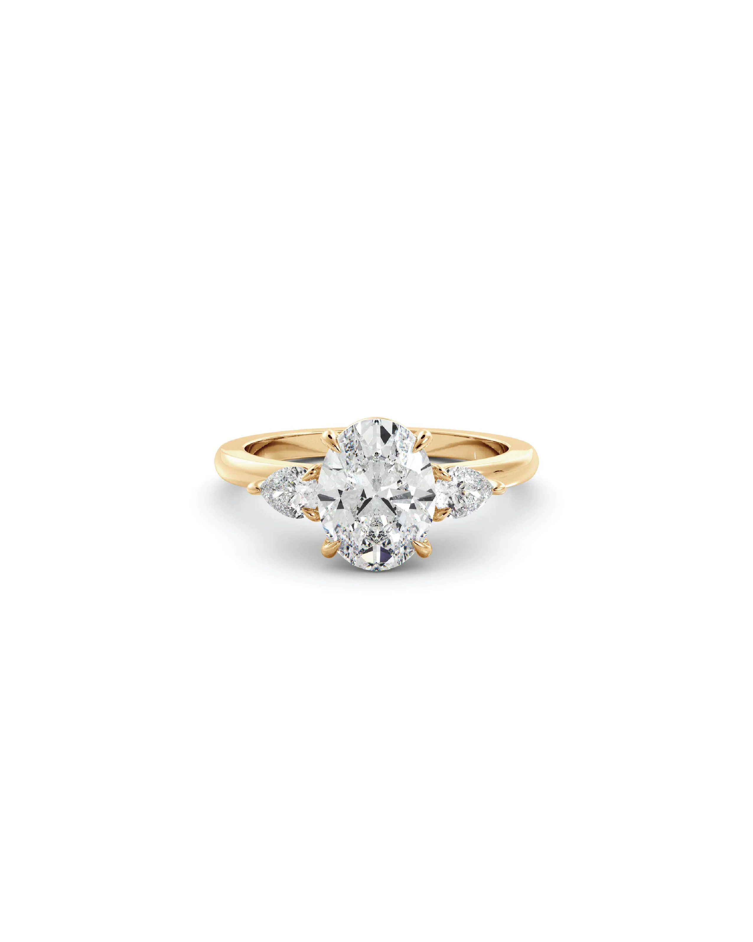 An 18K yellow gold three-stone ring with an oval central diamond and pear-shaped accent diamonds.