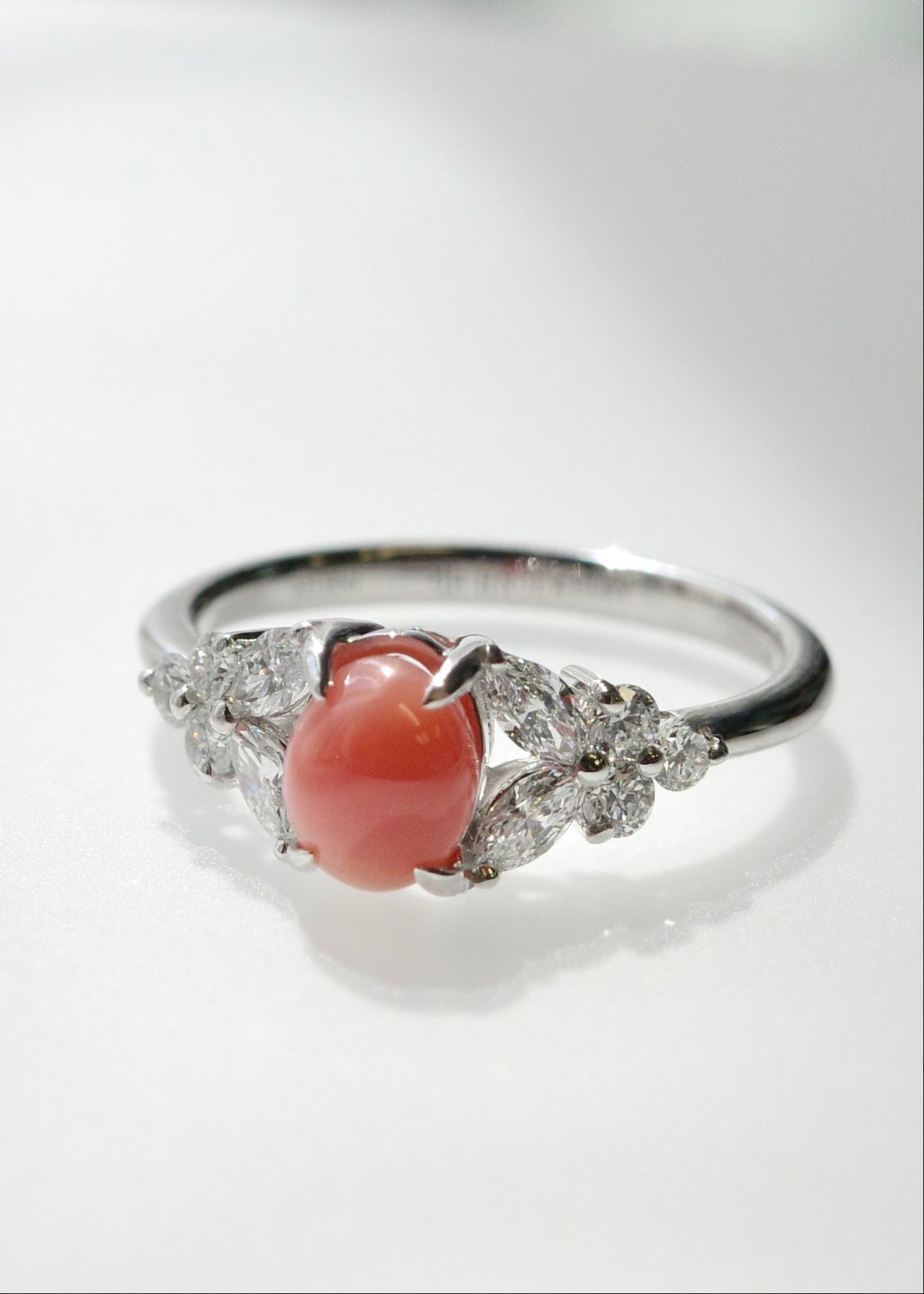 A  white gold ring featuring a natural conch pearl flanked by marquise diamond, photographed on a light gray reflective surface.