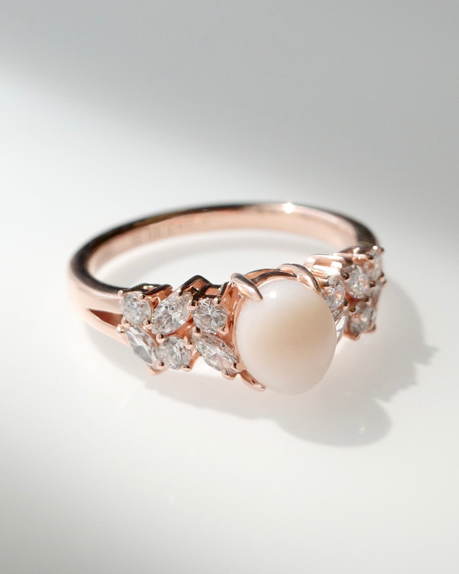 Side profile of the rose gold crown setting displaying the marquise diamond cluster wings flanking the natural conch pearl.