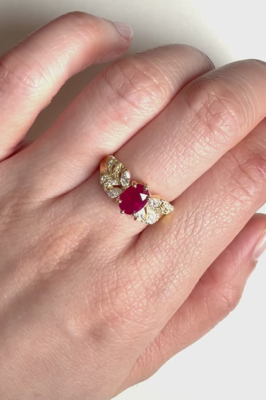 Red ruby engagement ring with round diamonds and leaf like butterfly side design