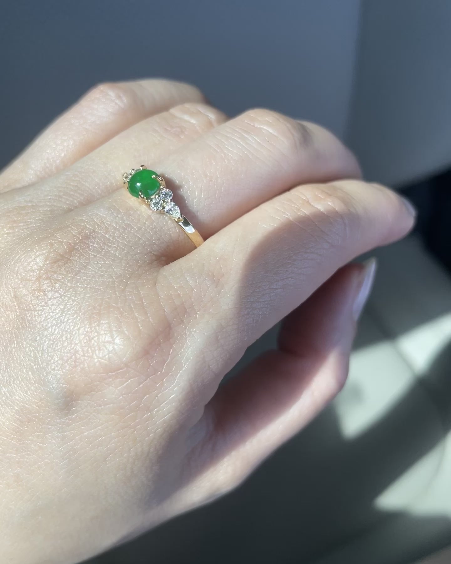 an unique engagement ring set with a 5mm natural round green jade at the center along with pear diamonds and round brilliant diamonds on the side