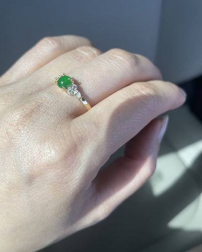 an unique engagement ring set with a 5mm natural round green jade at the center along with pear diamonds and round brilliant diamonds on the side