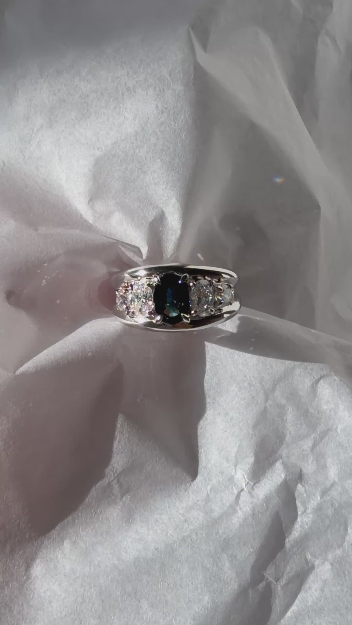 Five-stone ring setting featuring center oval teal sapphire, oval diamonds, and round diamonds.
