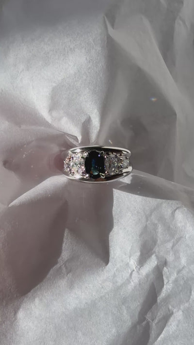 Five-stone ring setting featuring center oval teal sapphire, oval diamonds, and round diamonds.