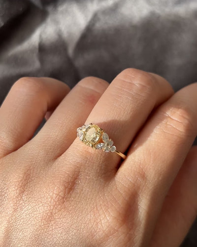An engagement ring set with oval cut fancy yellow diamond at the center along with marquise diamond on the side