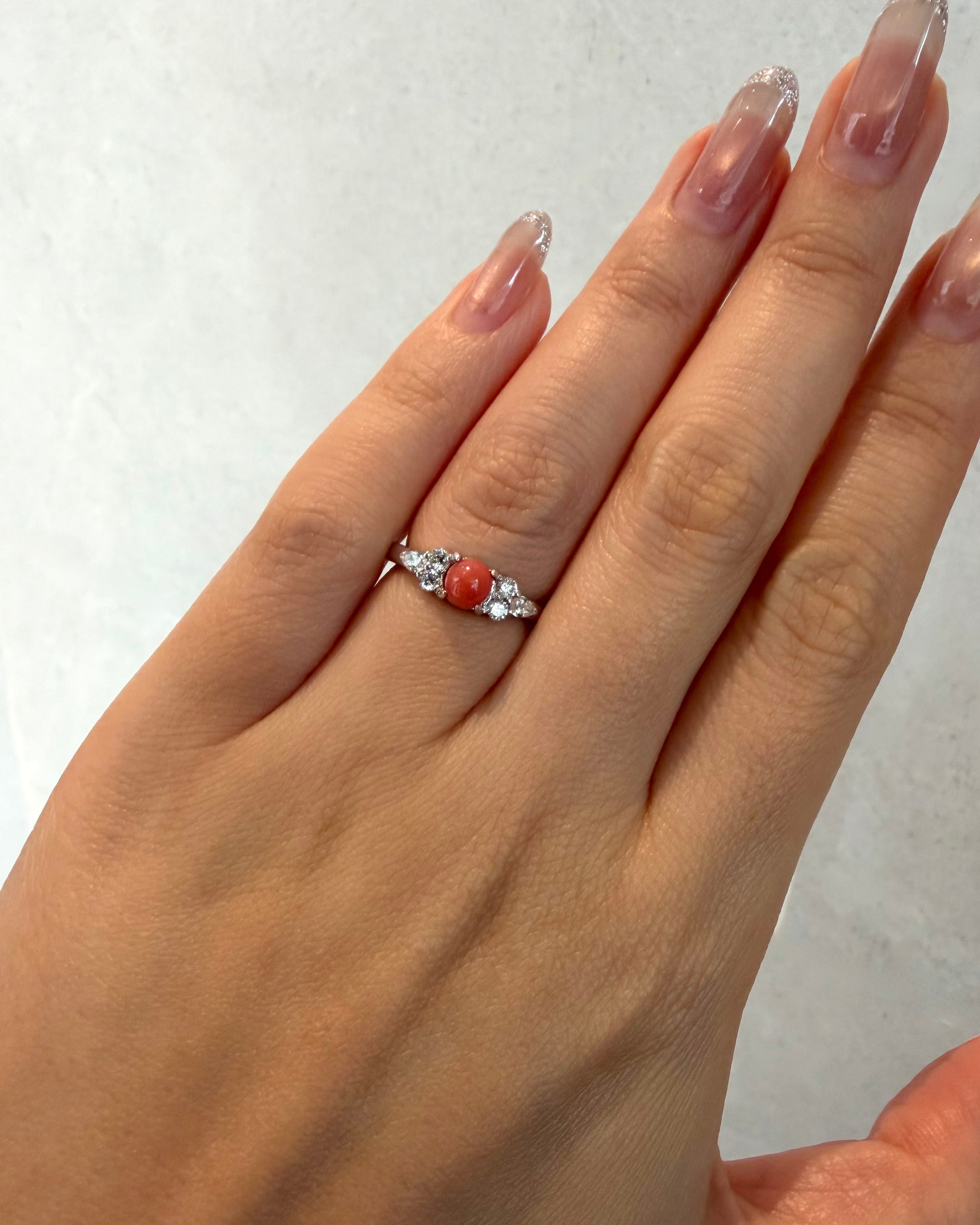 Female hand wearing the rare 0.68ct round red conch pearl and pear diamond cluster ring on ring finger.