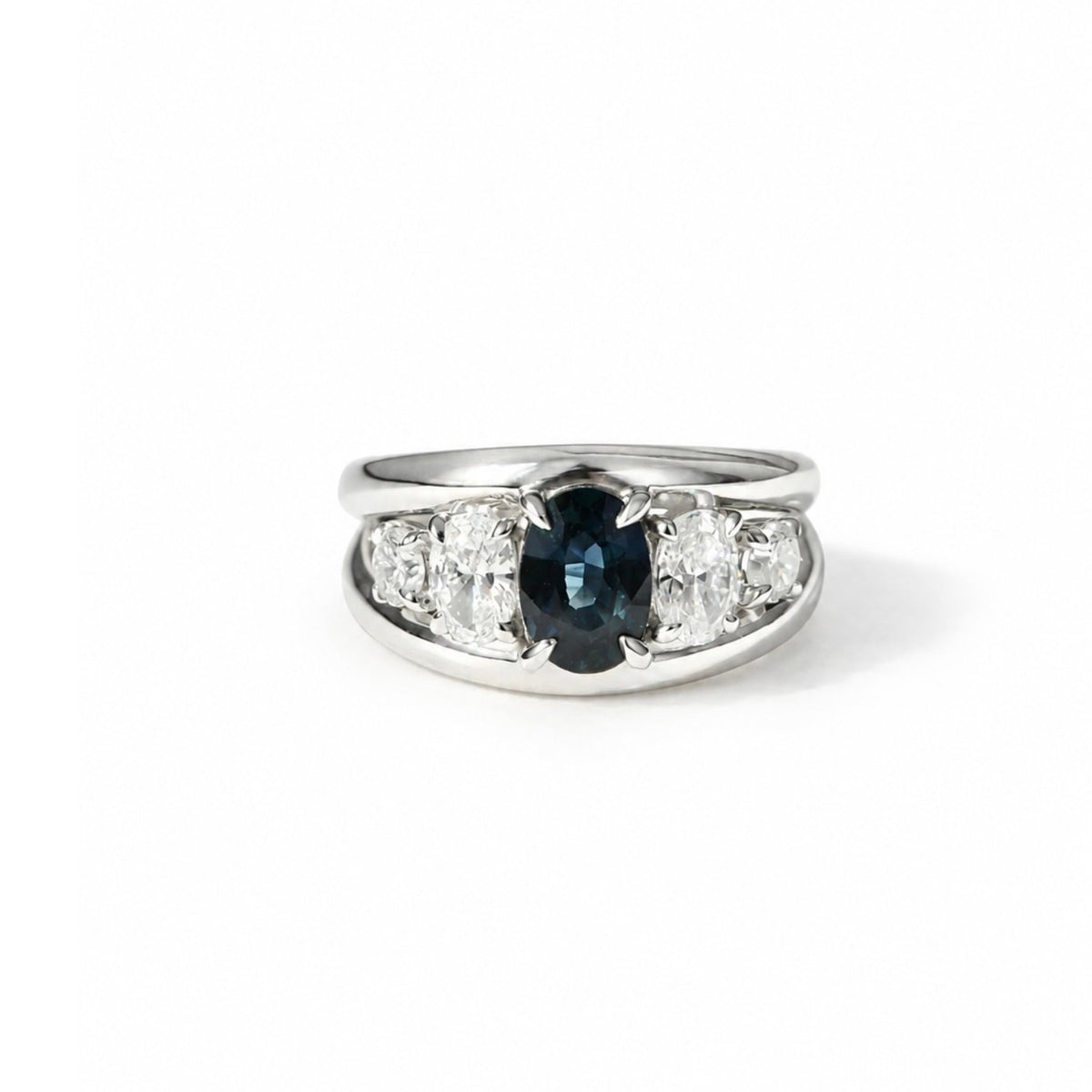 Macro close-up of deep teal sapphire center stone and diamond prongs in 14k white gold.